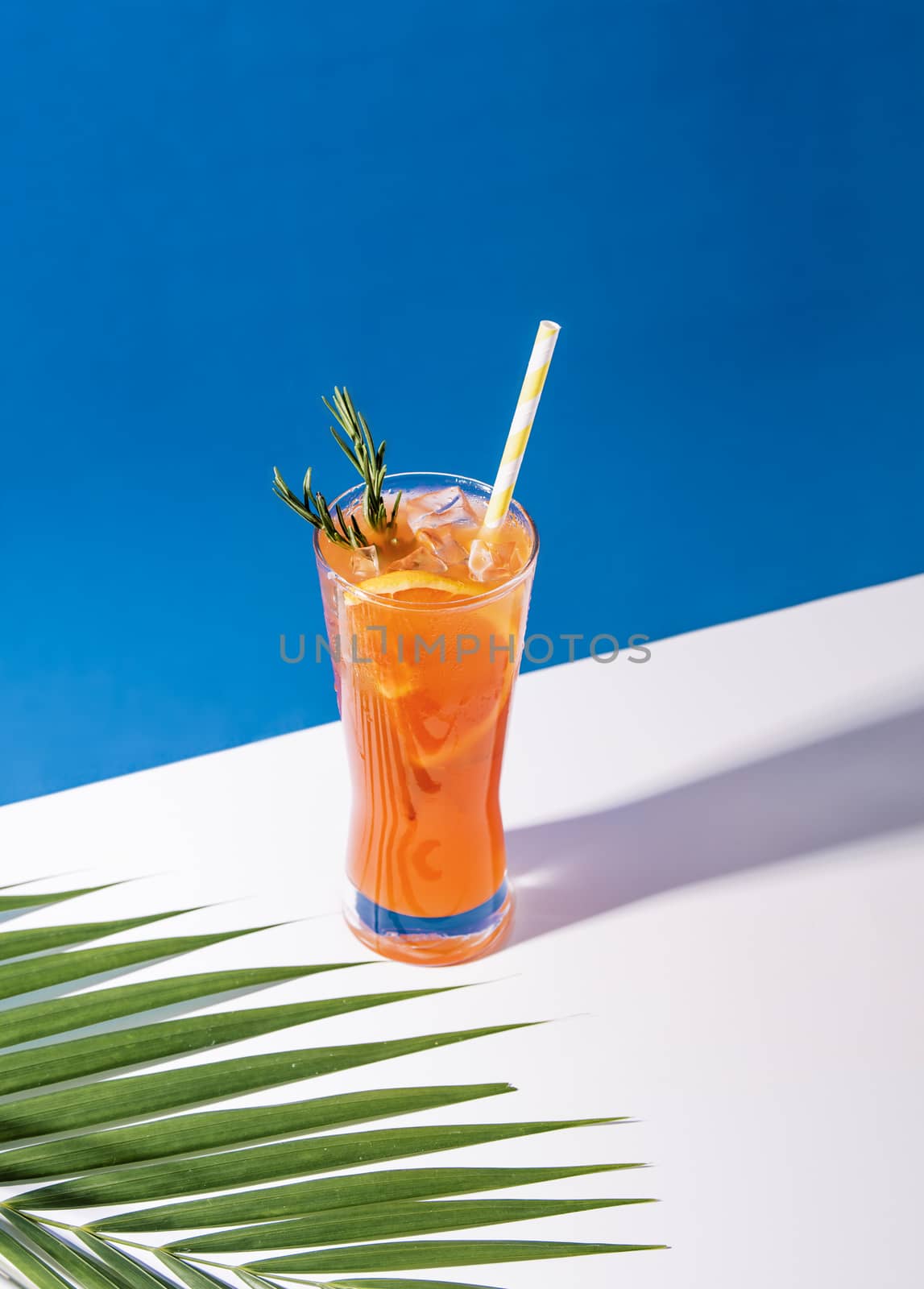 Cold and refreshing orange punch cocktail with orange slice on blue background. summer drink.