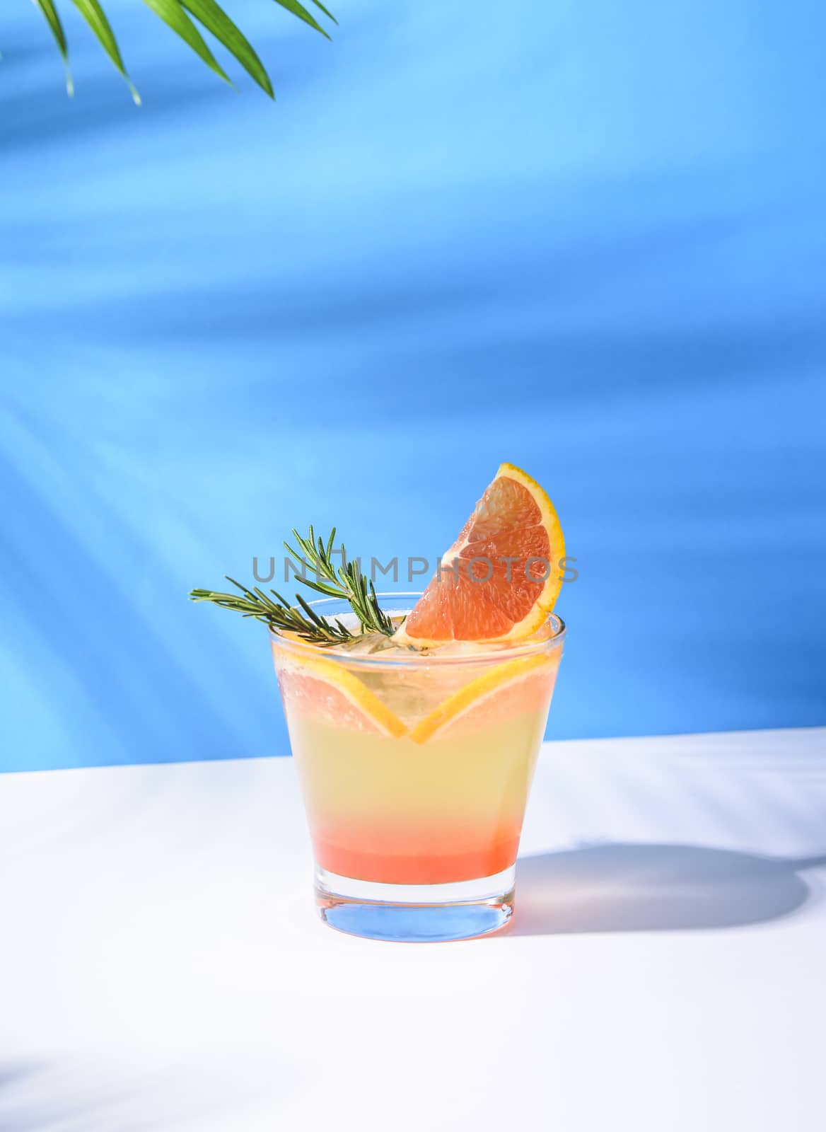 Cold and refreshing orange punch cocktail with orange slice on blue background. summer drink.