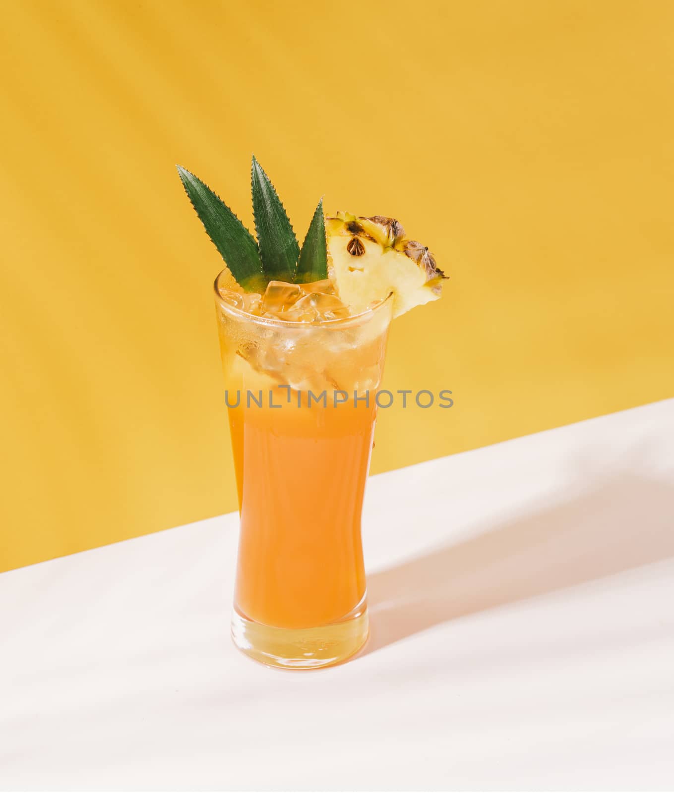 iced pineapple punch cocktail in glass on orange background. summer drink.