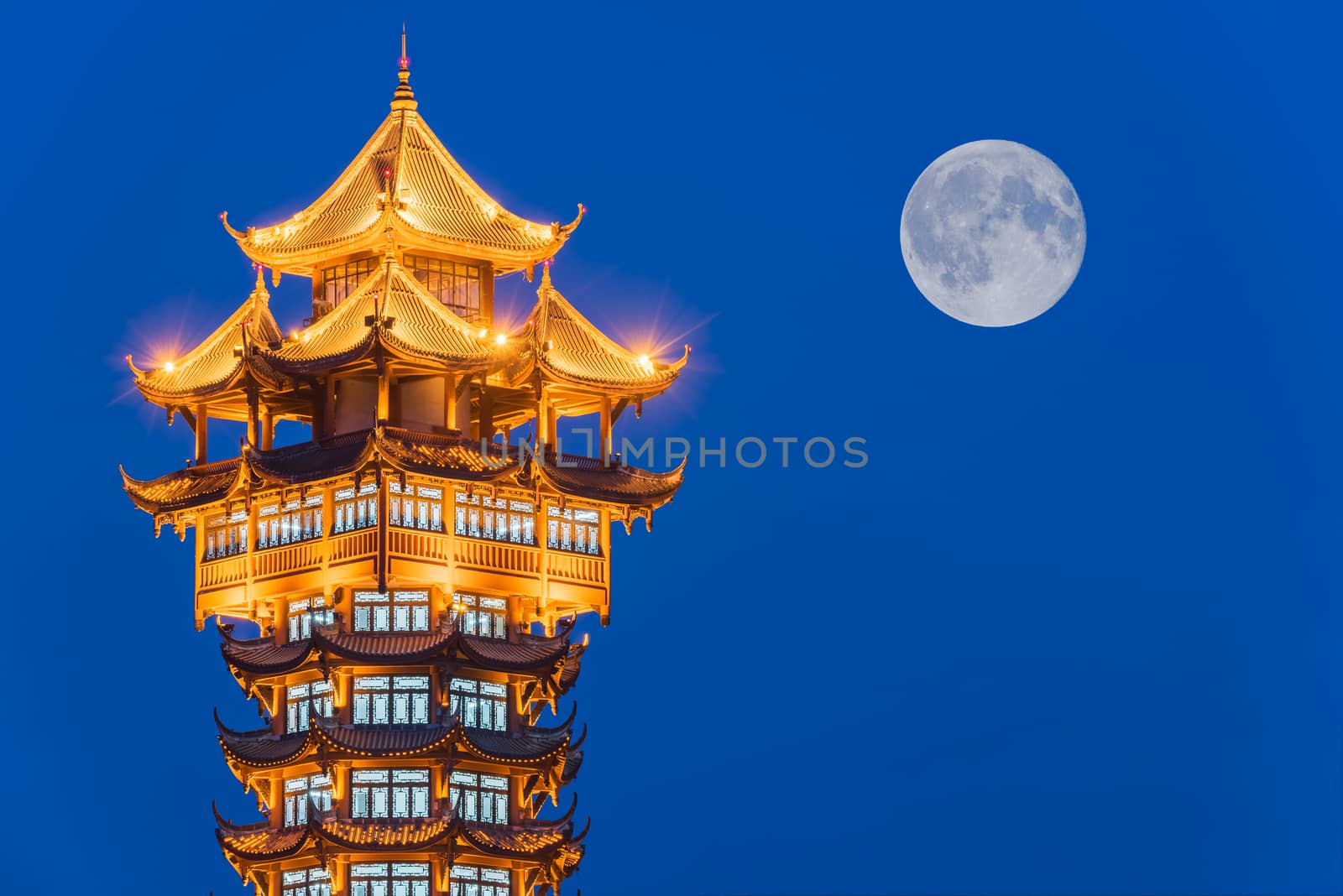 Jiutian traditional tower illuminated at night with full moon in the background, Chengdu, China