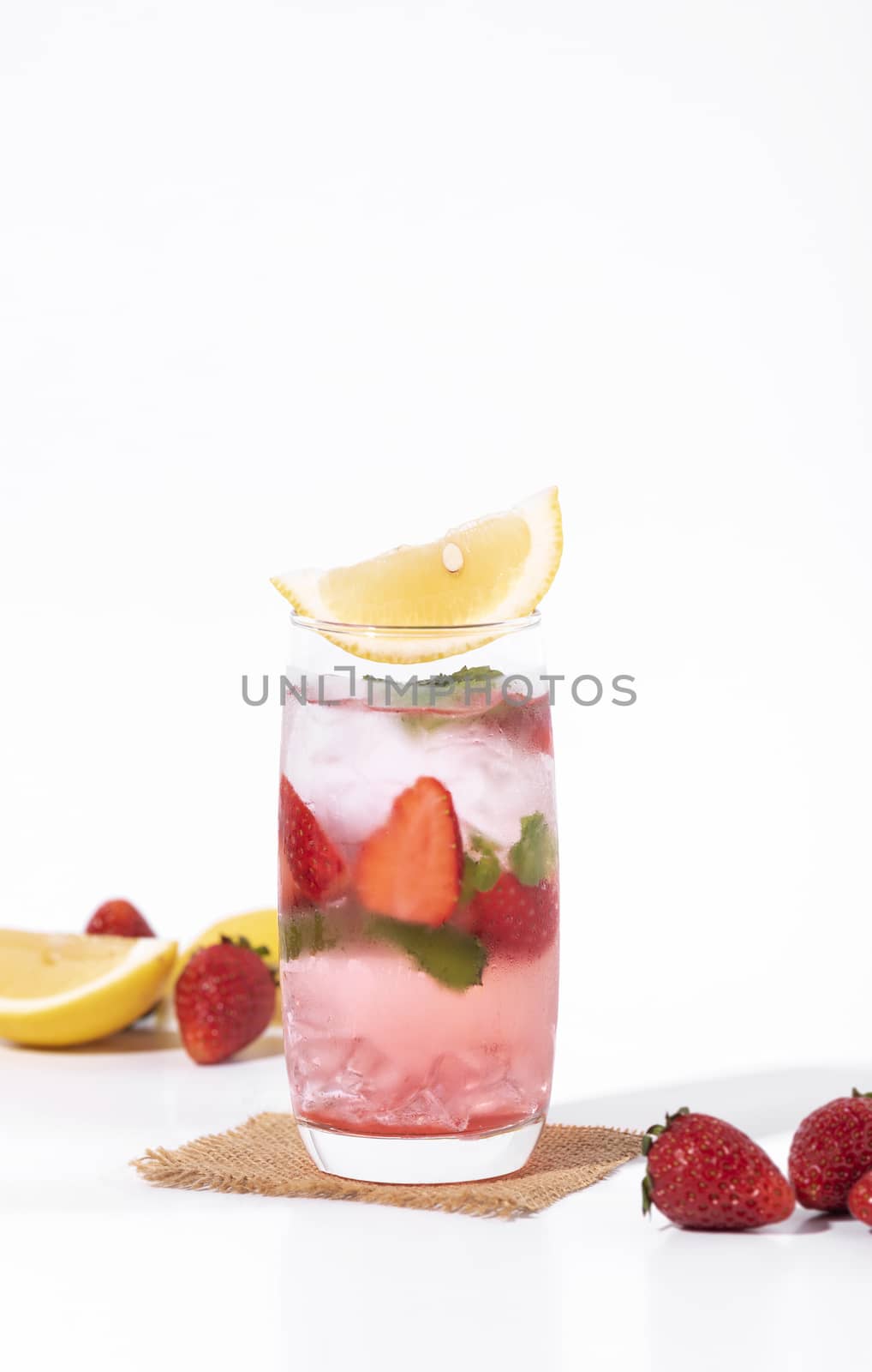 iced strawberry punch cocktail in glass with lemon on white background. summer drink.