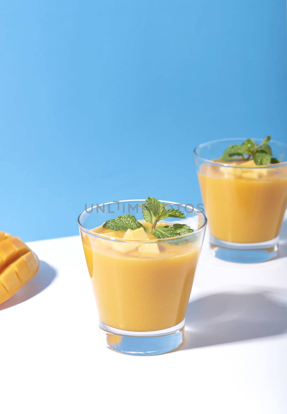 Fresh mango smoothie and ripe mango slice on color background. summer drink.