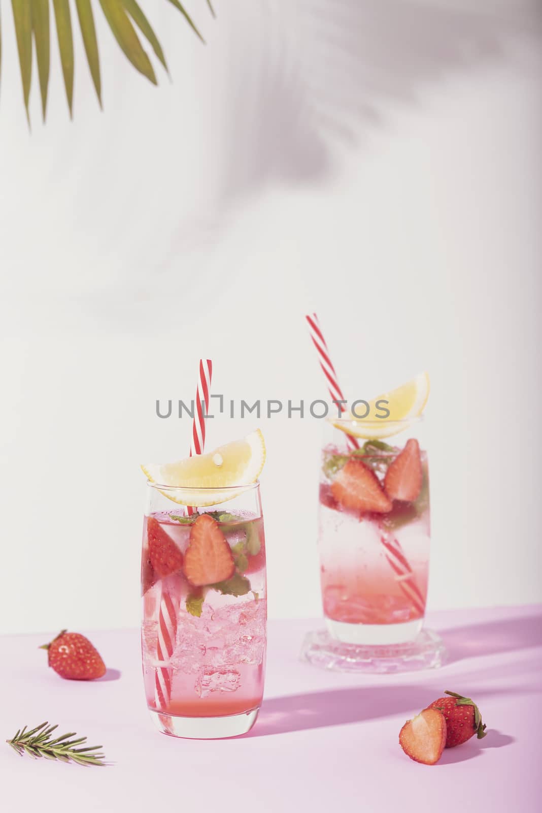 iced strawberry punch cocktail in glass with lemon on white background. summer drink.