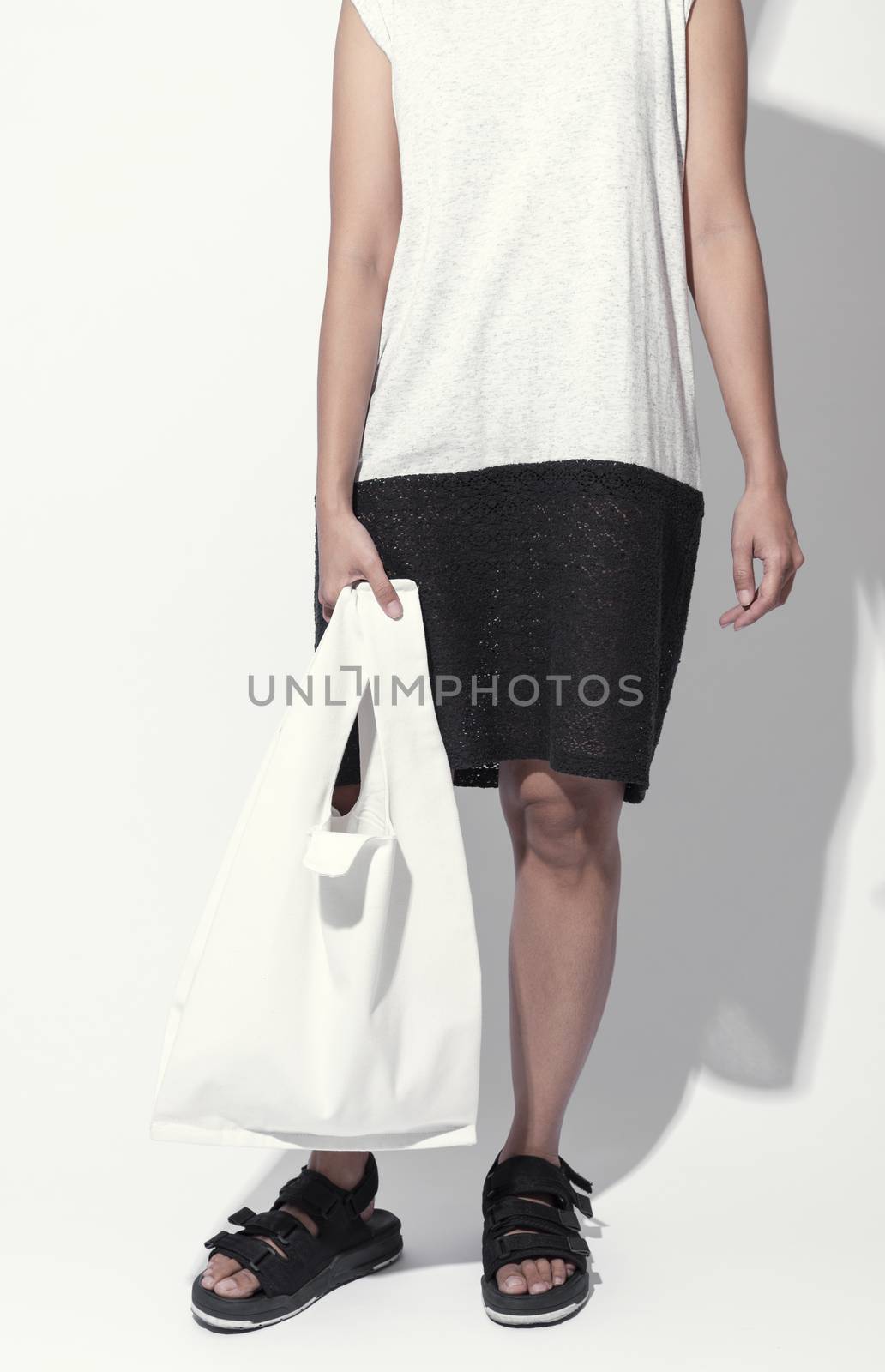Girl is holding bag canvas fabric for mockup blank template isolated on gray background.