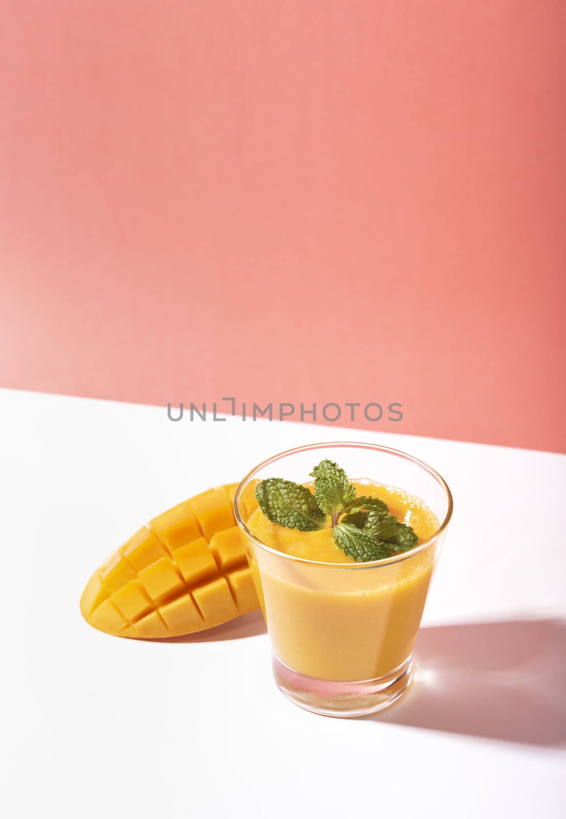 Fresh mango smoothie and ripe mango slice on color background. summer drink.