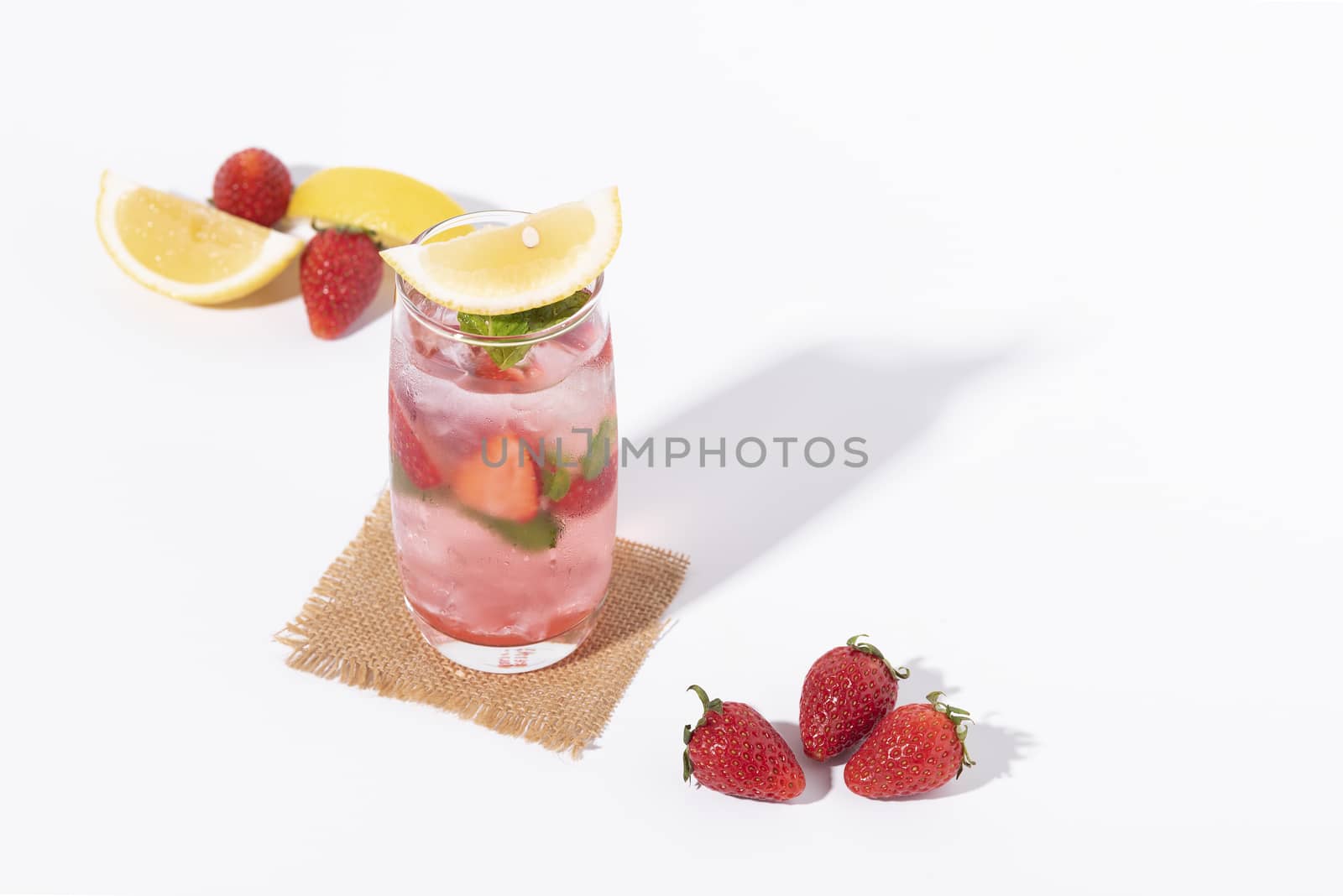 iced strawberry punch cocktail in glass with lemon on white background. summer drink.