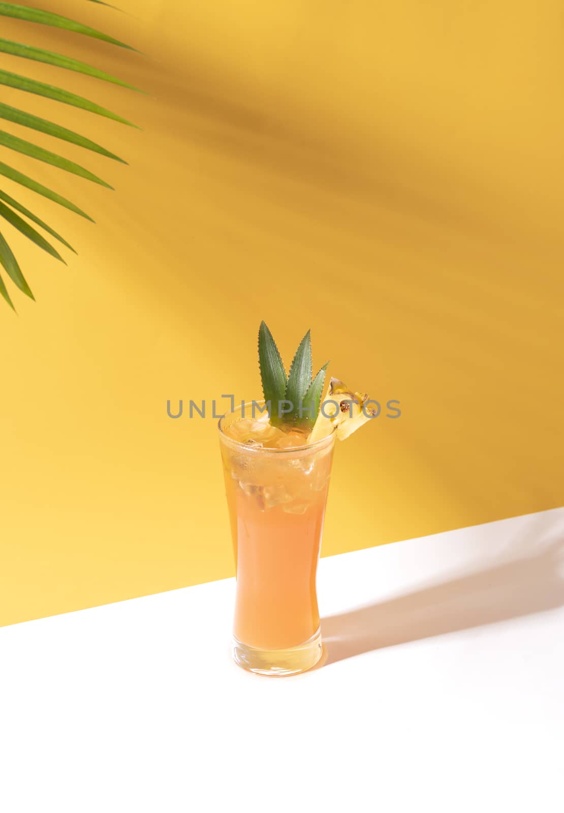 iced pineapple punch cocktail in glass on orange background. summer drink.