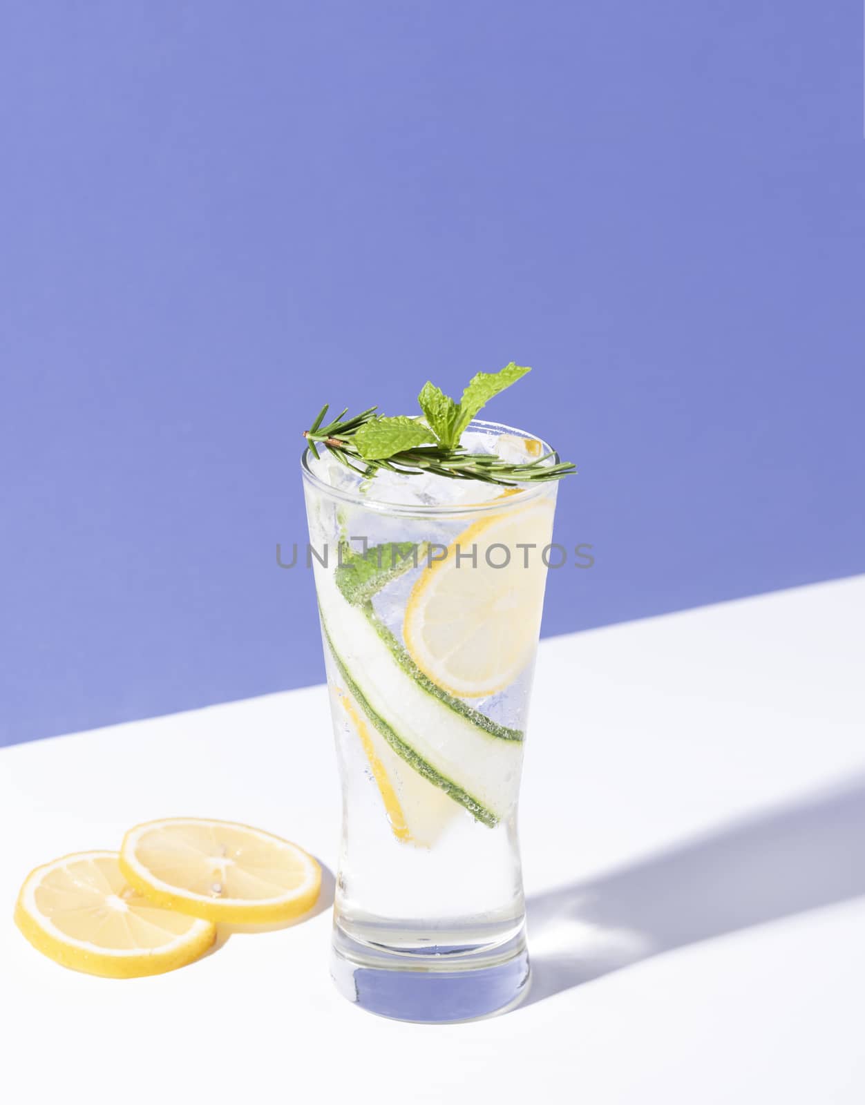 Mojito cocktail with lemon and mint in glass on blue background. summer drink.