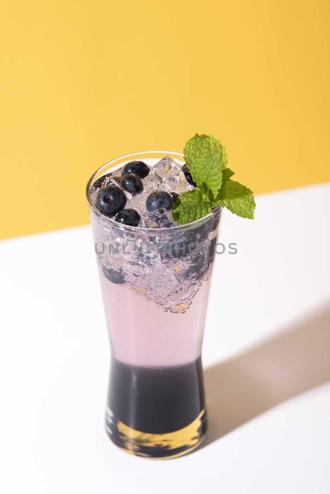 Cold and refreshing  blueberry punch cocktail with mint on color background. summer drink