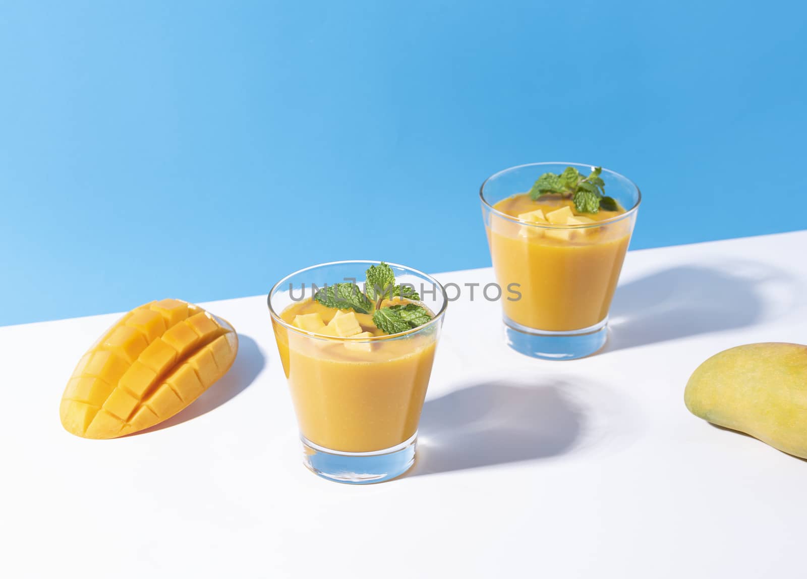 Fresh mango smoothie and ripe mango slice on color background. summer drink.