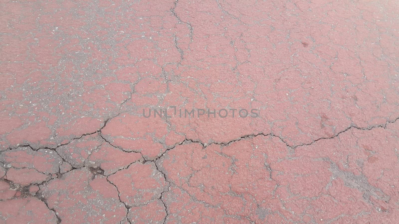 Red colored damaged road or paved pathway with crackes by Photochowk