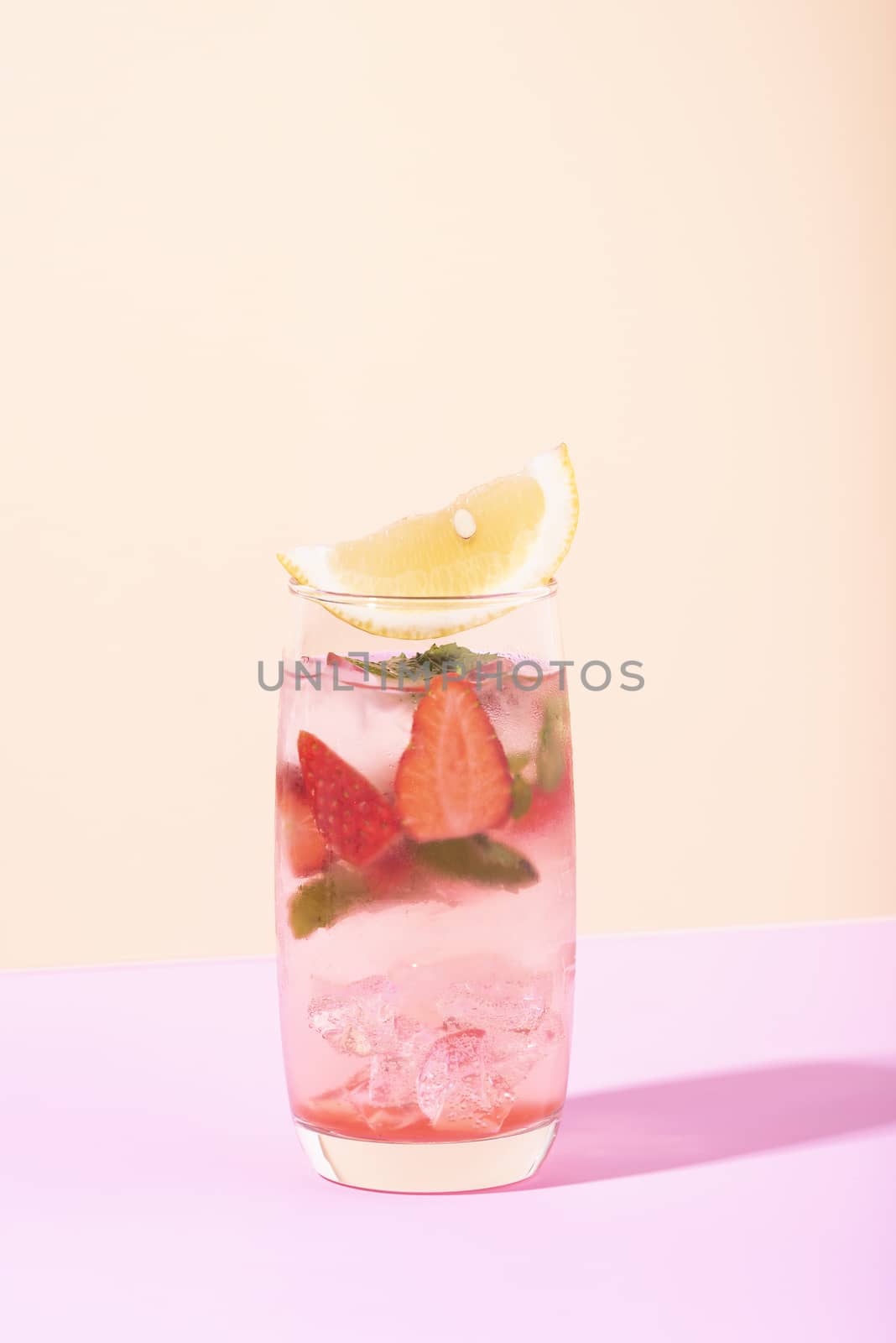 iced strawberry punch cocktail in glass with lemon on color background. summer drink.