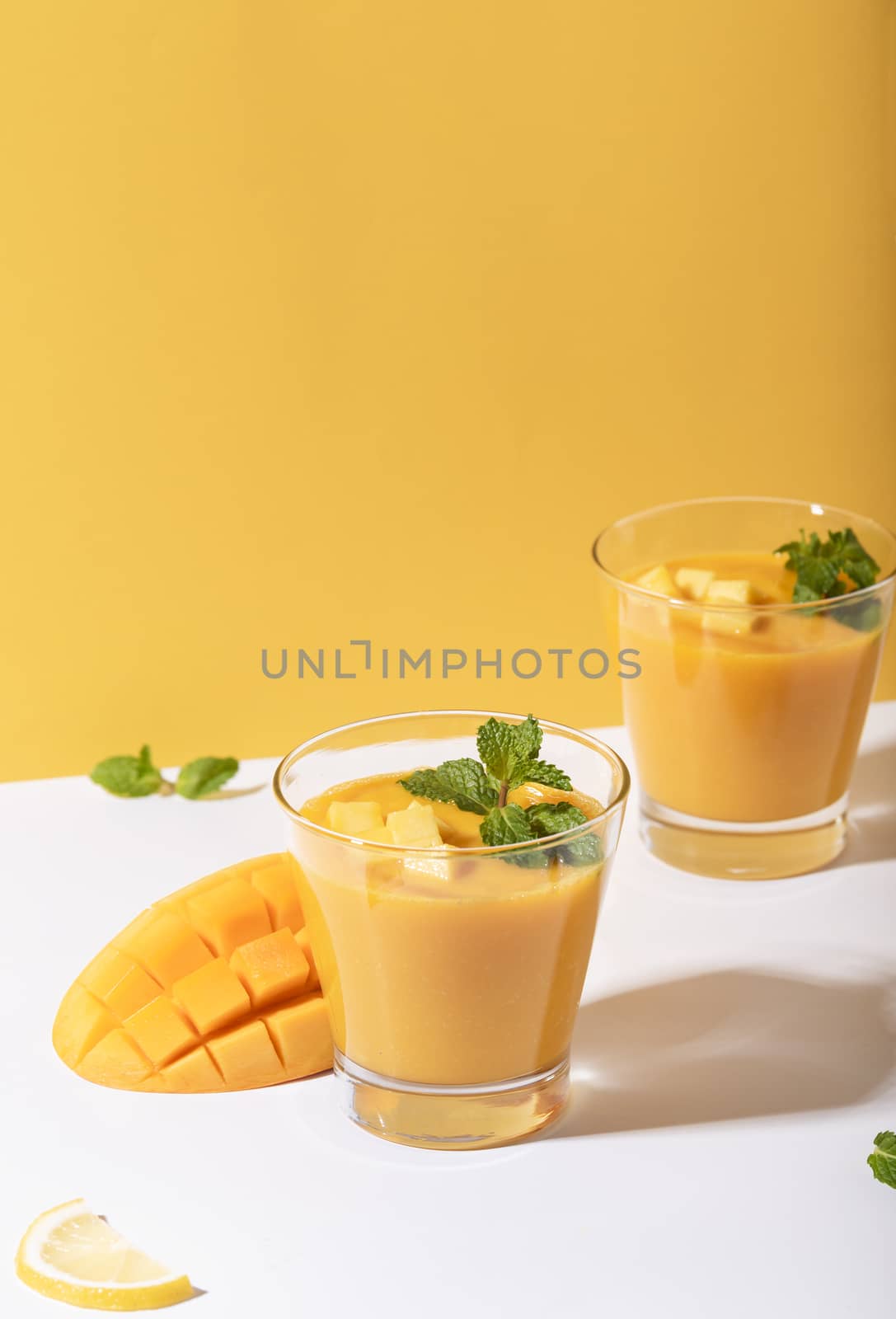 Fresh mango smoothie and ripe mango slice on color background. summer drink.