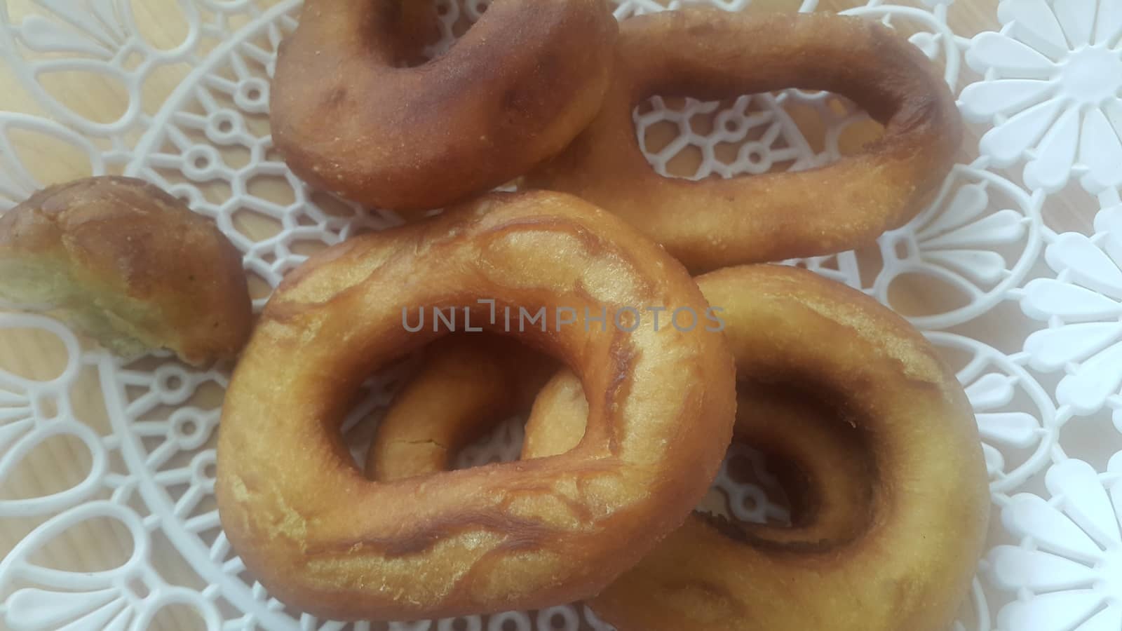 Closeup view of a set of freshly prepared donuts served on white changair. Donuts are placed in a changair over wooden floor