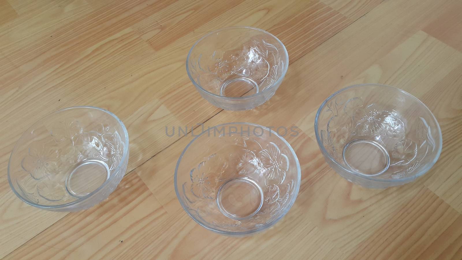 Top view of empty white glass bowls on a wooden floor. Glass bowl with flowers made on its wall