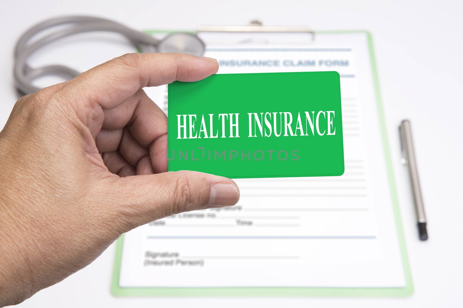 Health insurance member card in someone hand with insurance claim form in background.