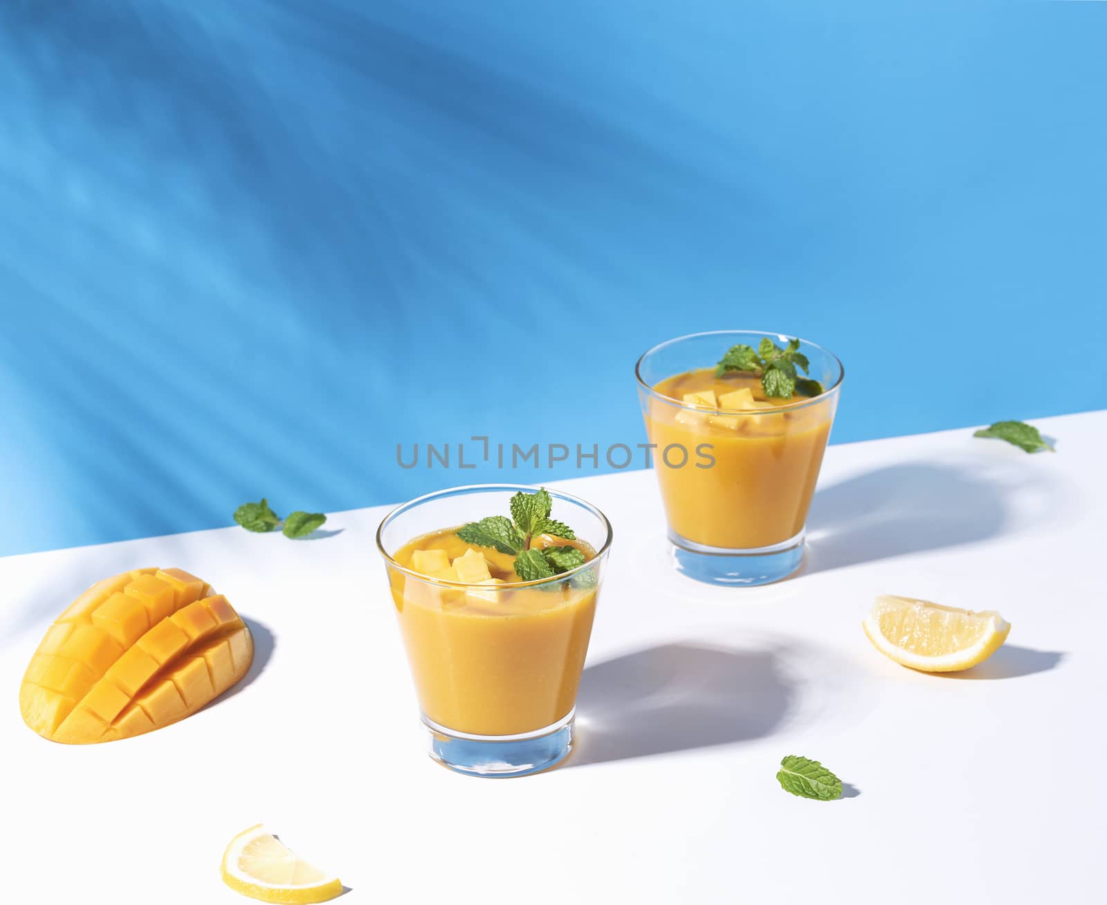 Fresh mango smoothie and ripe mango slice on color background. summer drink.