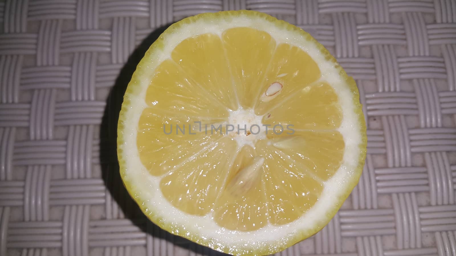 Fresh lemon slices with yellow peelings placed on a grey floor by Photochowk