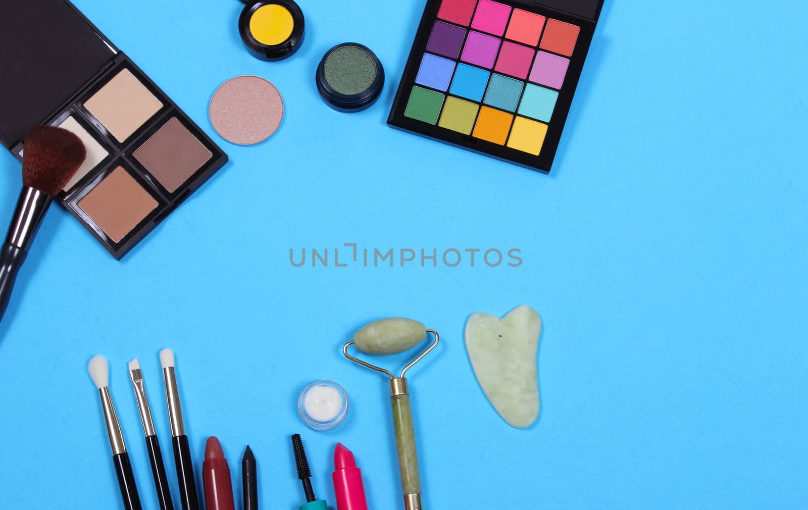 Cosmetics and Brushes on textured blue paper background