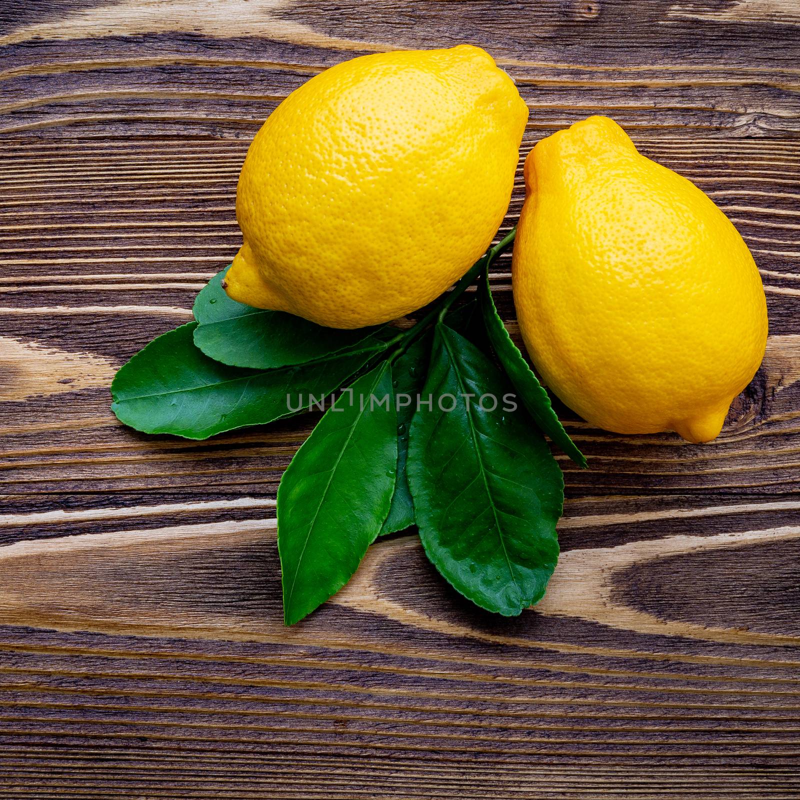 Fresh lemons and  lemons leaves on shabby wooden background. by kerdkanno