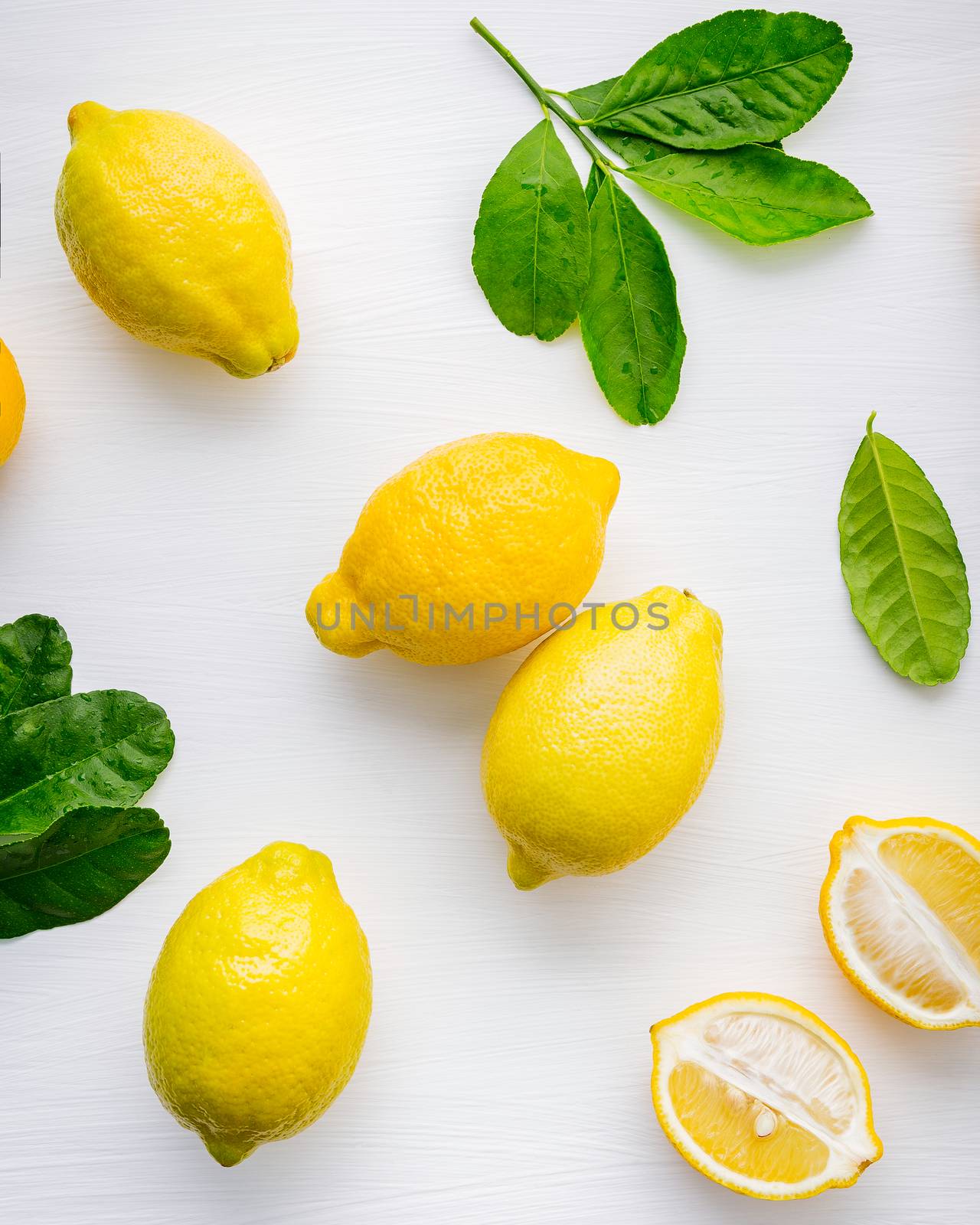 Fresh lemons and  lemons leaves on white wooden background.