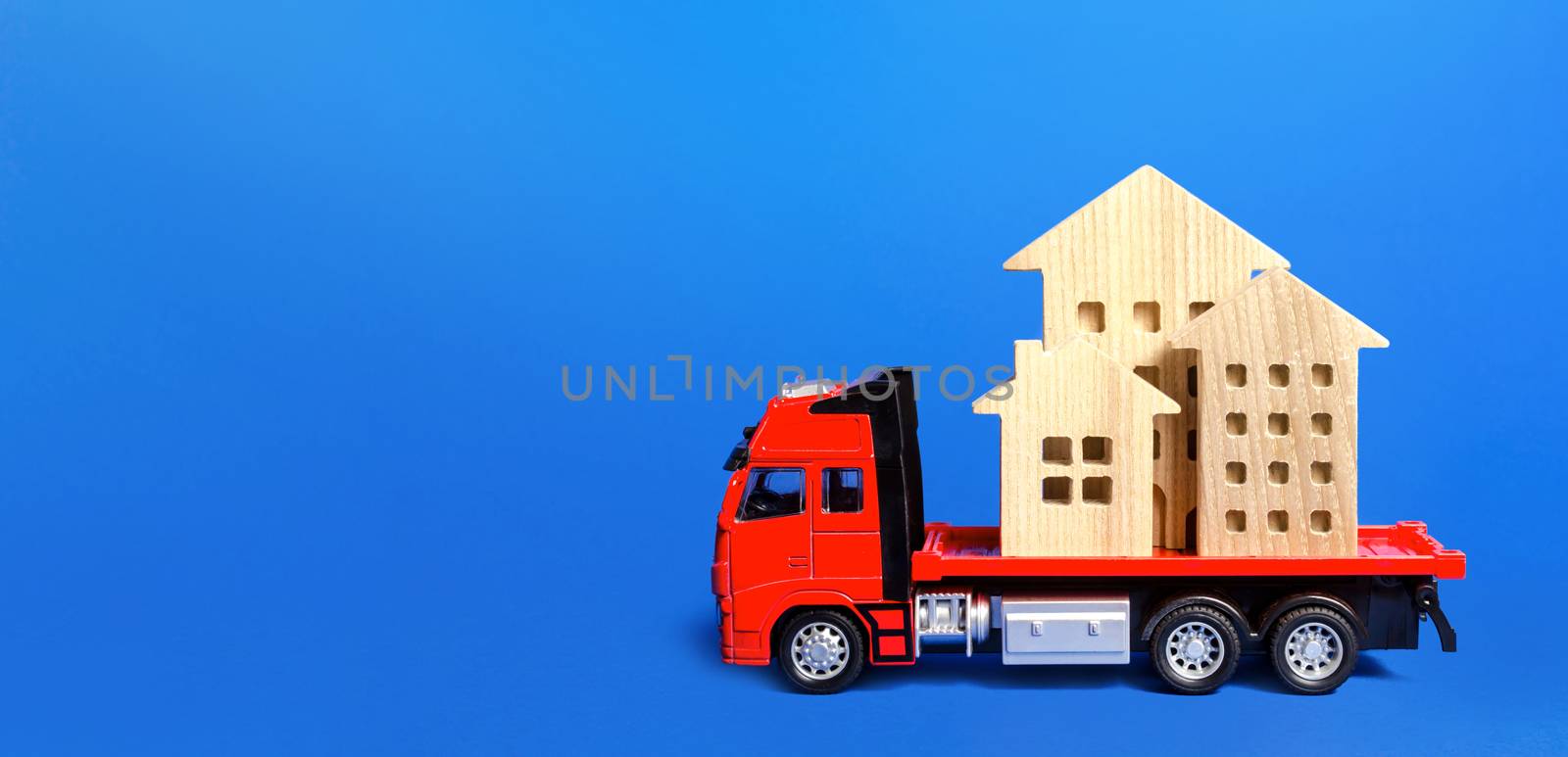 Red freight truck loaded with figure houses. Relocation of buildings and monuments. Cargo transportation, delivery service. A moving company. Infrastructure and logistics industry. Place for text by iLixe48