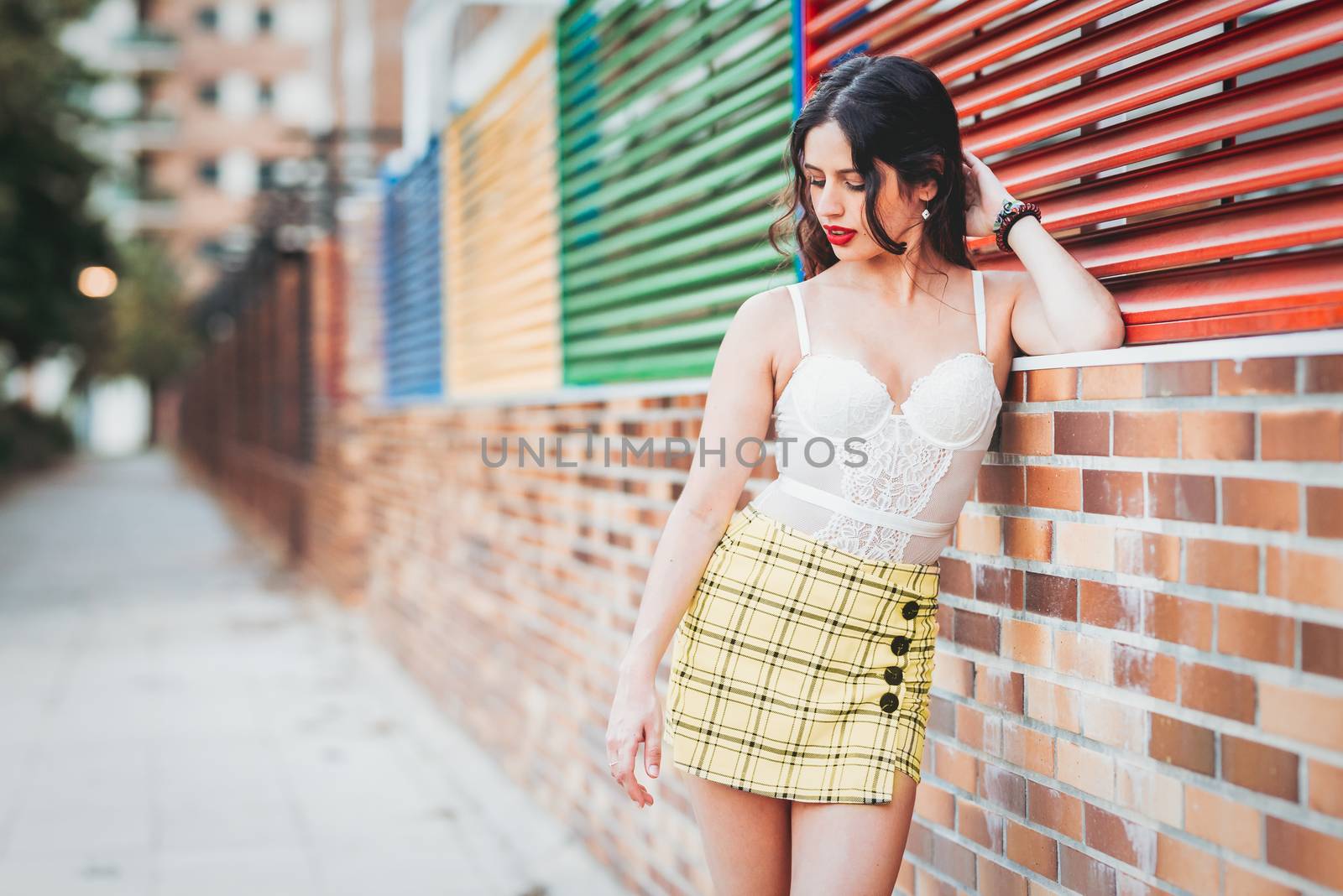 woman lean against a wall in a skort and bodysuite.