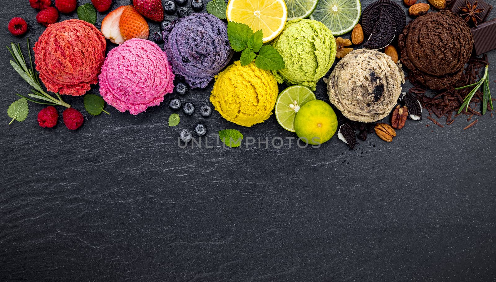 Various of ice cream flavor ball blueberry ,lime ,pistachio ,almond ,orange ,chocolate and vanilla set up on dark stone background . Summer and Sweet menu concept.