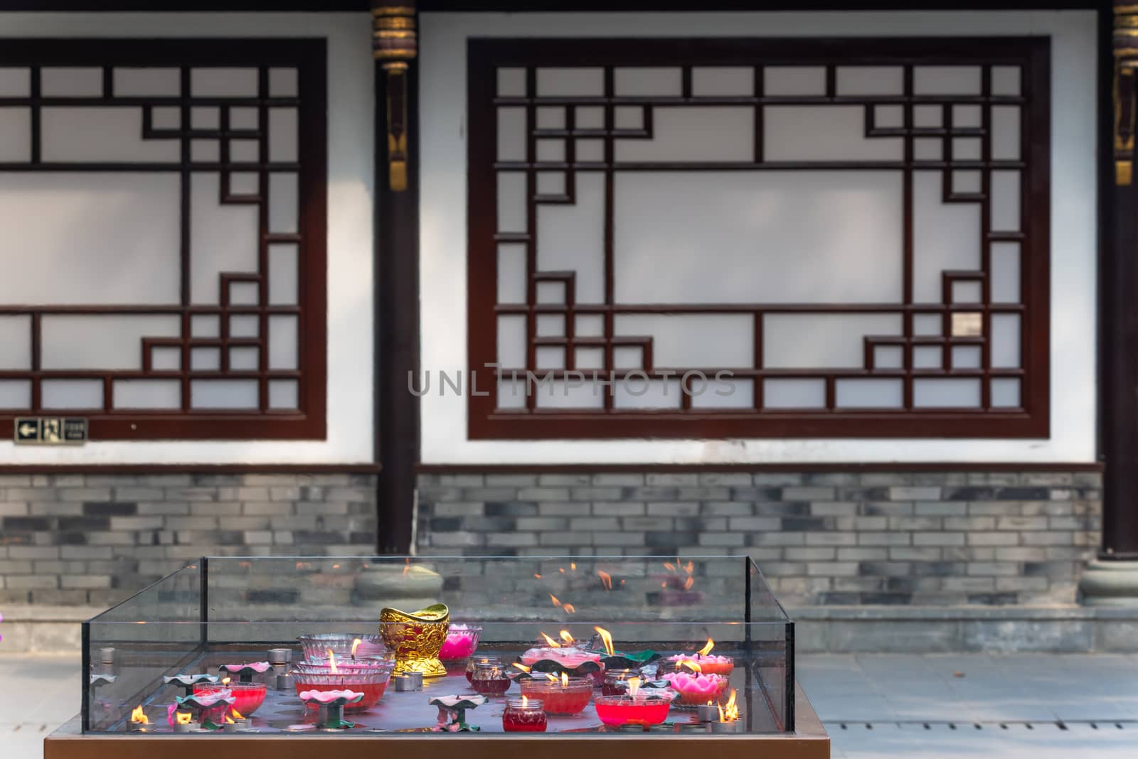 Candles burning in Daci buddhist temple roof against modern building in Chengdu, China