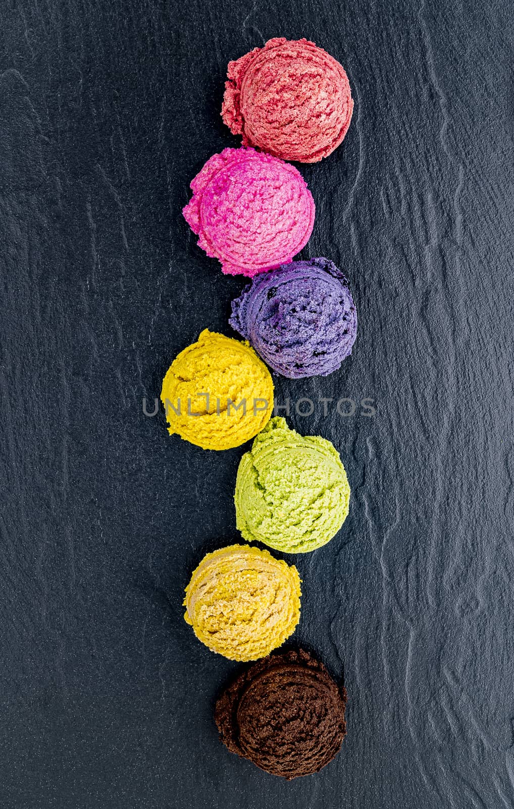 Various of ice cream flavor ball blueberry ,lime ,pistachio ,almond ,orange ,chocolate and vanilla set up on dark stone background . Summer and Sweet menu concept.