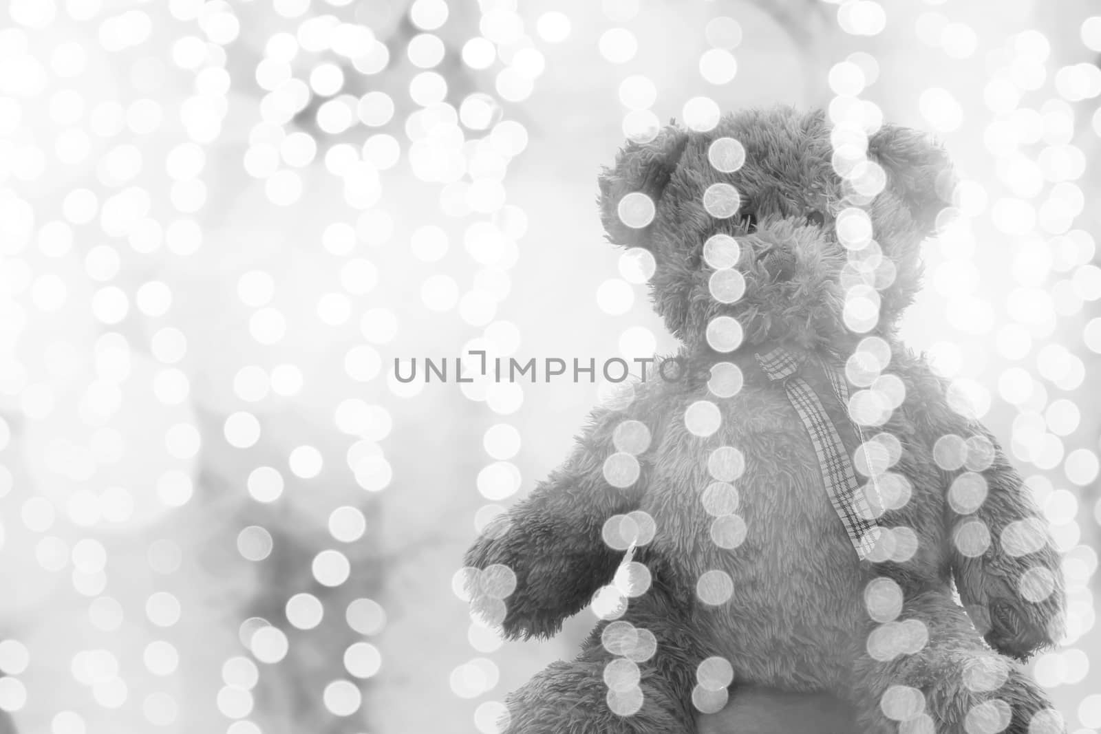 Teddy bear doll in Lighting line bokeh silver bright for Christmas or happy new year Background, Bear Sitting lonely in glitter Gray white background Blurred bokeh bright (Selective Focus)