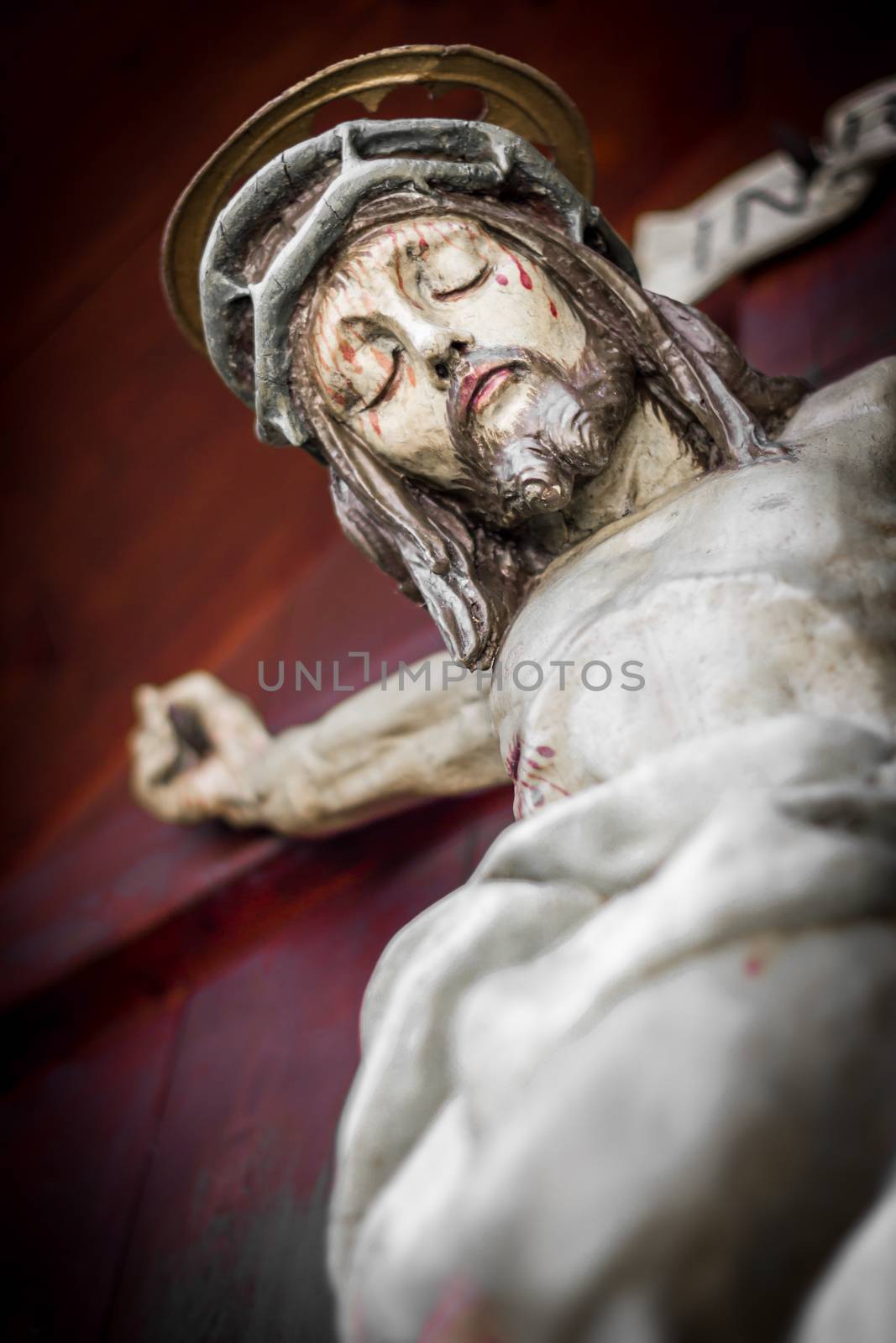 The bleeding body of Jesus Christ, crucified on a wooden cross. Shallow depth of field.