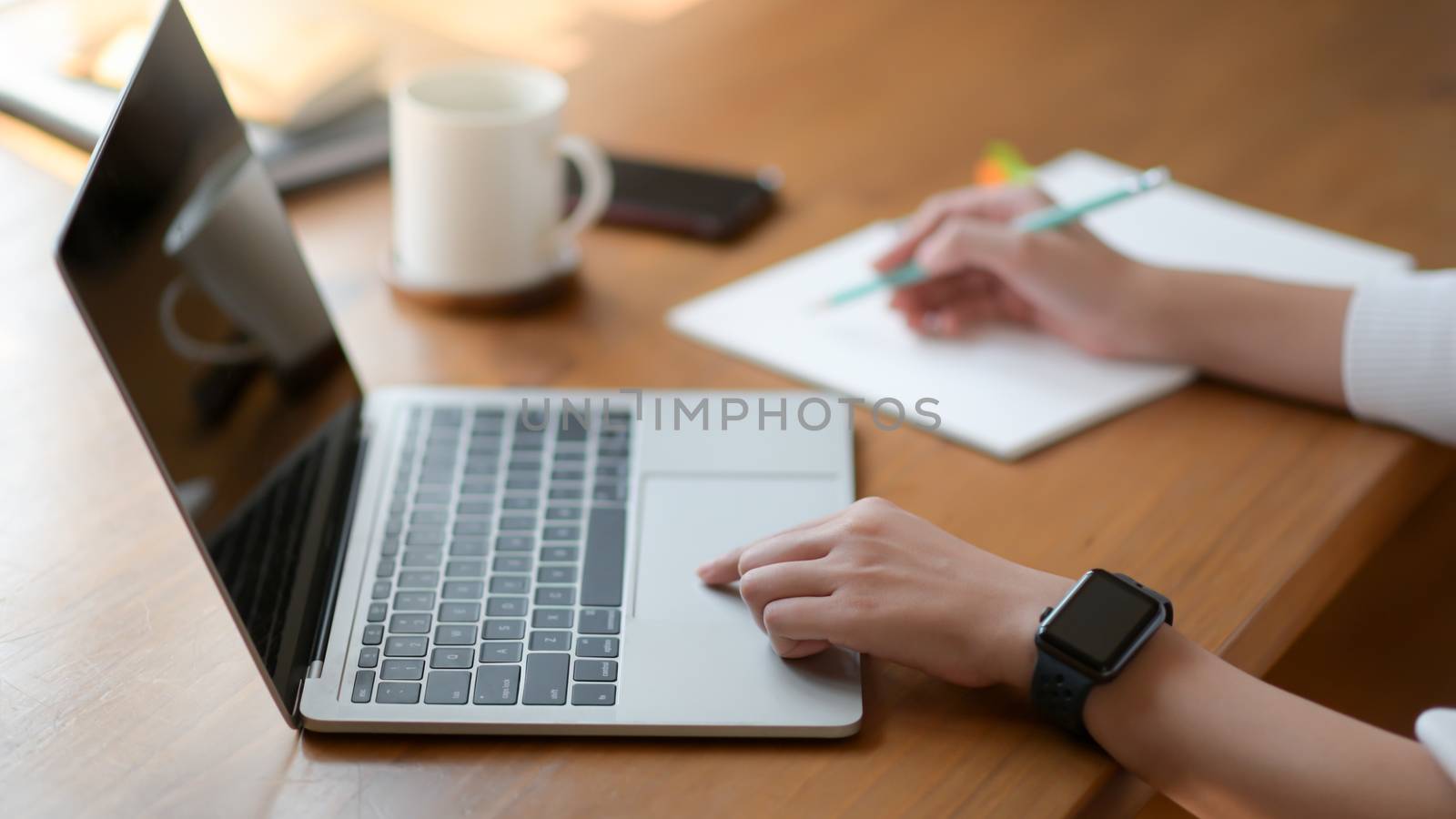 The hand of a young woman using a laptop and writing a report, S by poungsaed