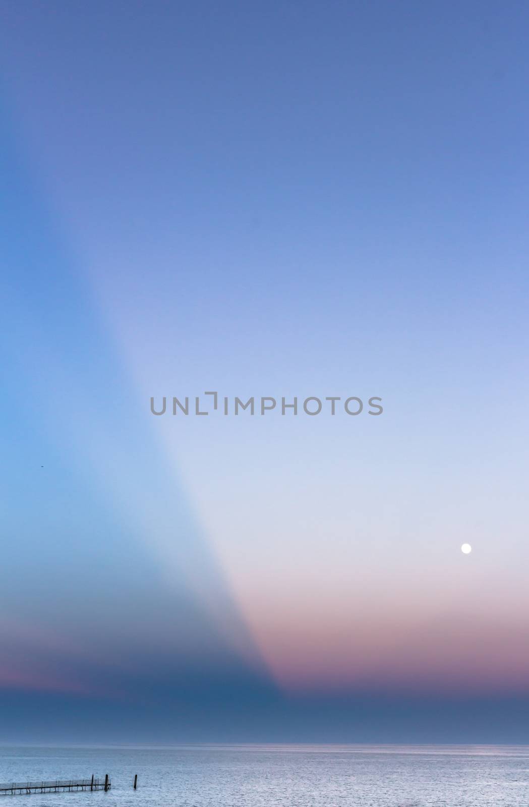 Abstract and dramatic sunset with light rays that create the shape of an inverted pyramid on the sea.