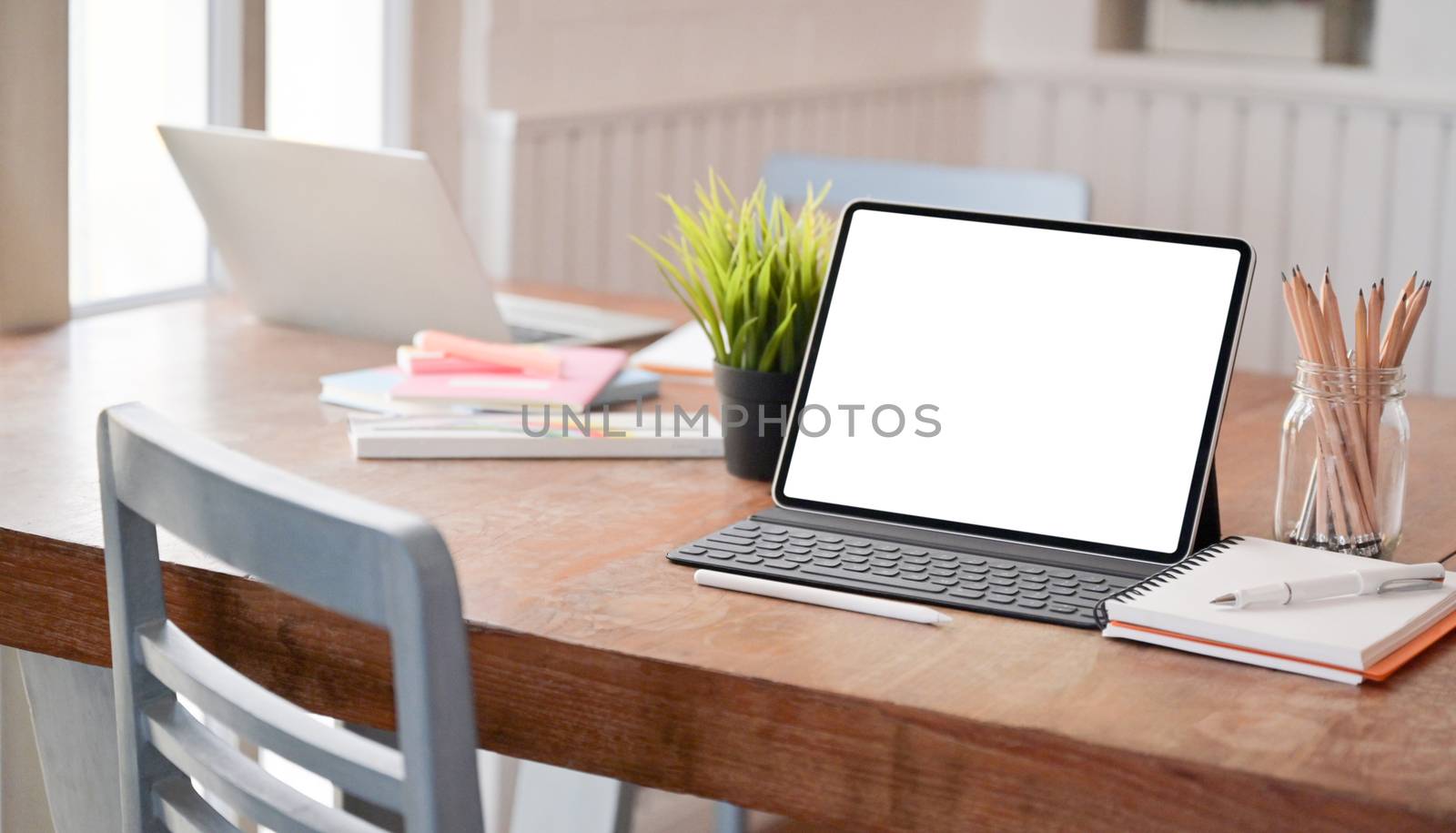 Mock up modern tablet and office equipment on the desk in a comf by poungsaed
