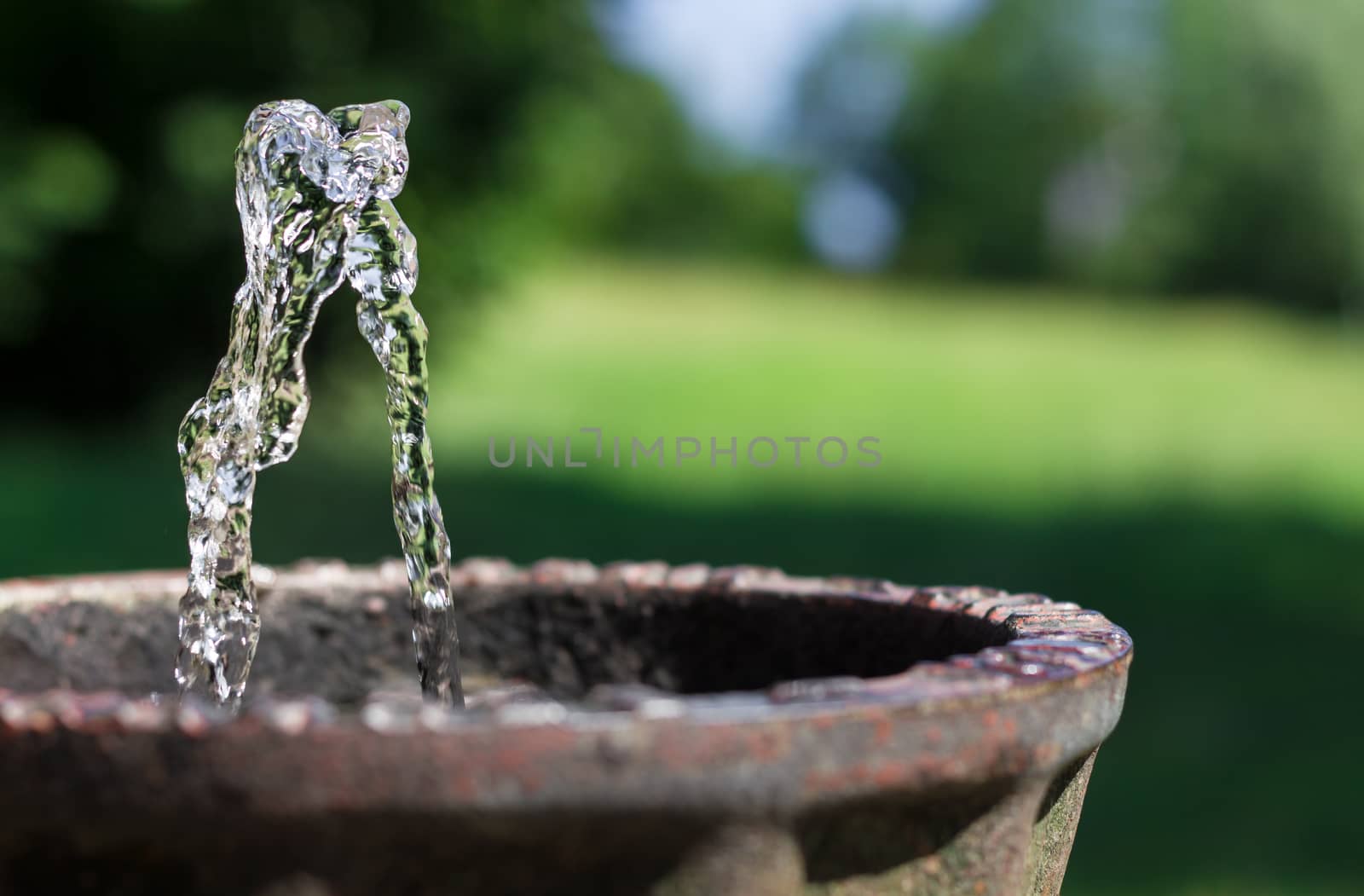 Water to drink in a vintage fountain, extreme closeup. Defocused blurry background.