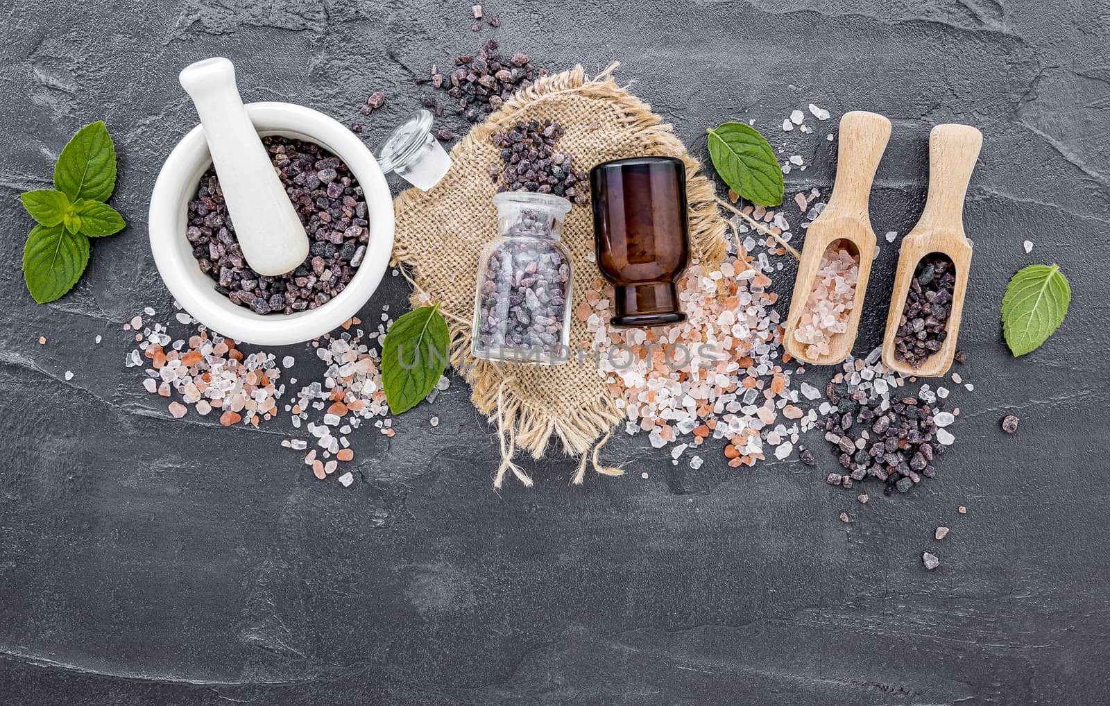 Himalayan black salt and Himalayan pink salt with peppermint  on dark concrete background. Himalayan salt commonly used in cooking and for bath products such as bath salts.