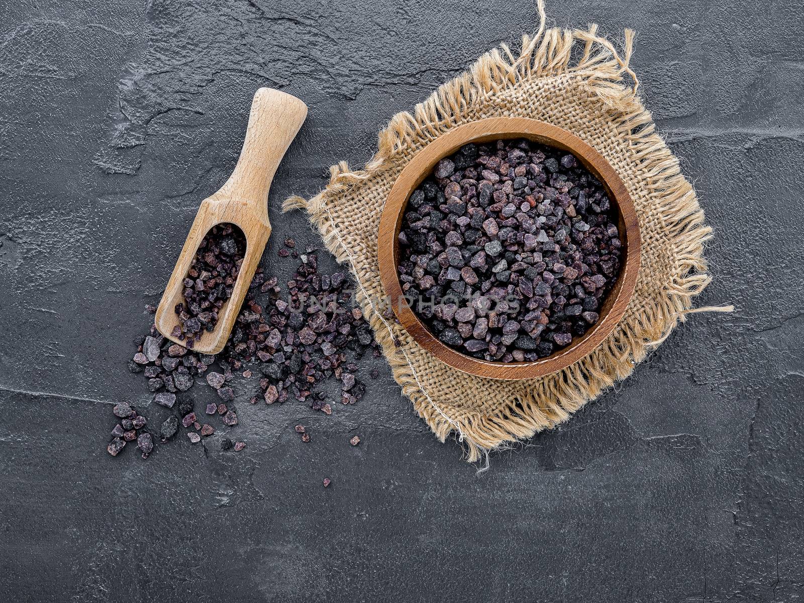 Himalayan black salt and Himalayan pink salt on dark concrete background. Himalayan salt commonly used in cooking and for bath products such as bath salts.