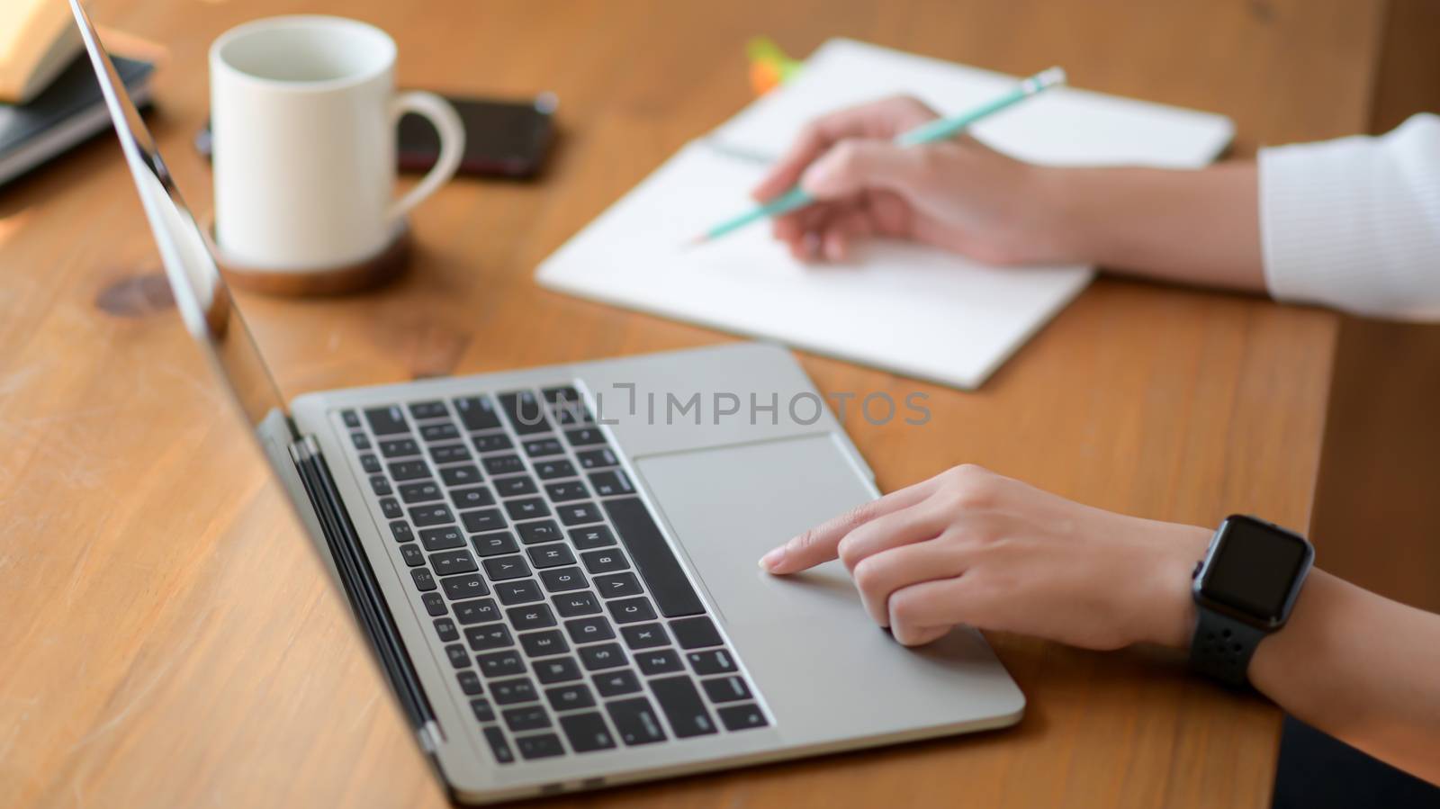 The hand of a young woman using a laptop and writing a report, S by poungsaed