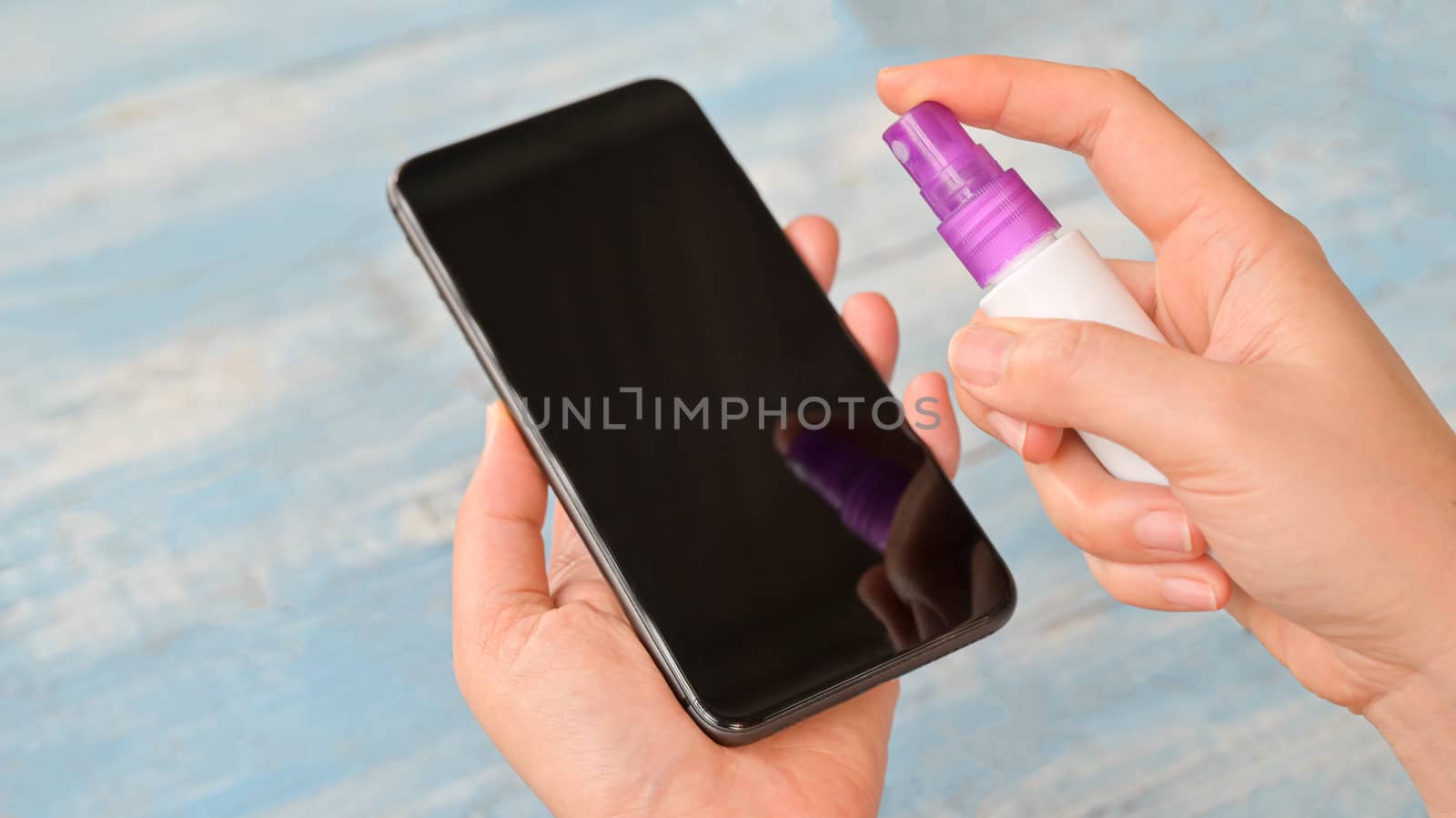 Close-up shot of Spray and wipe the alcohol to clean and kill germs on the smartphone.