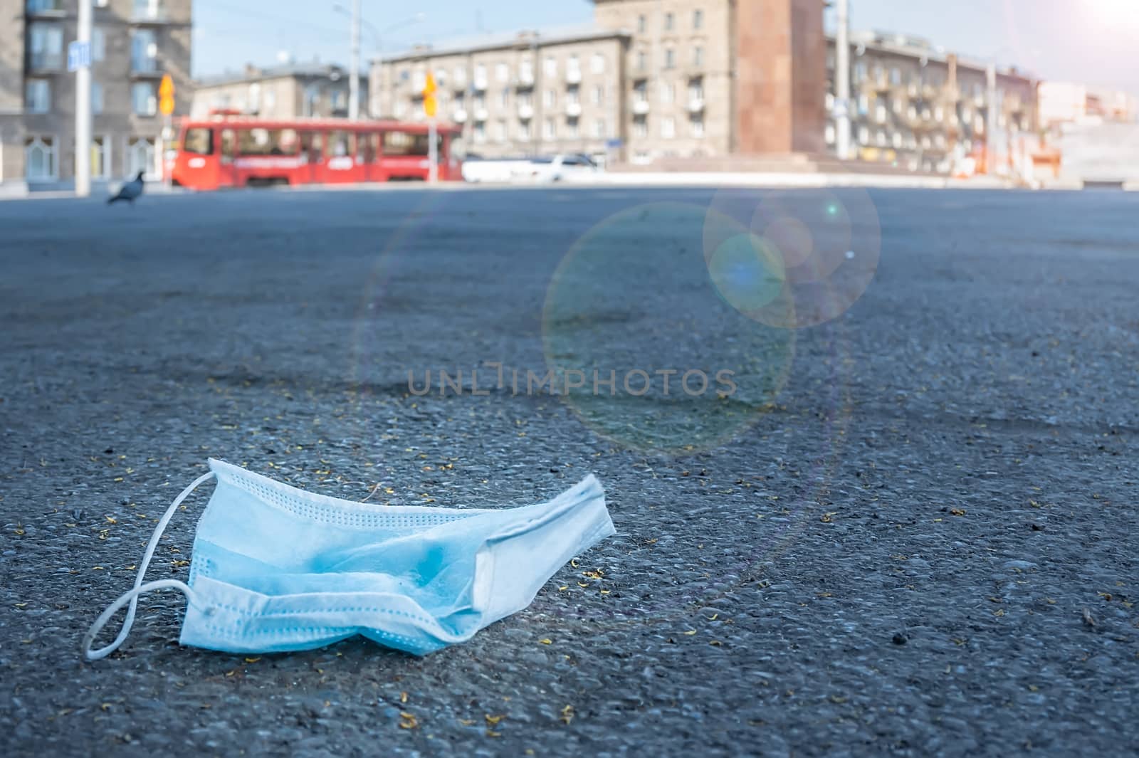 abandoned and used antibacterial medical mask lies on the pavement in a city park