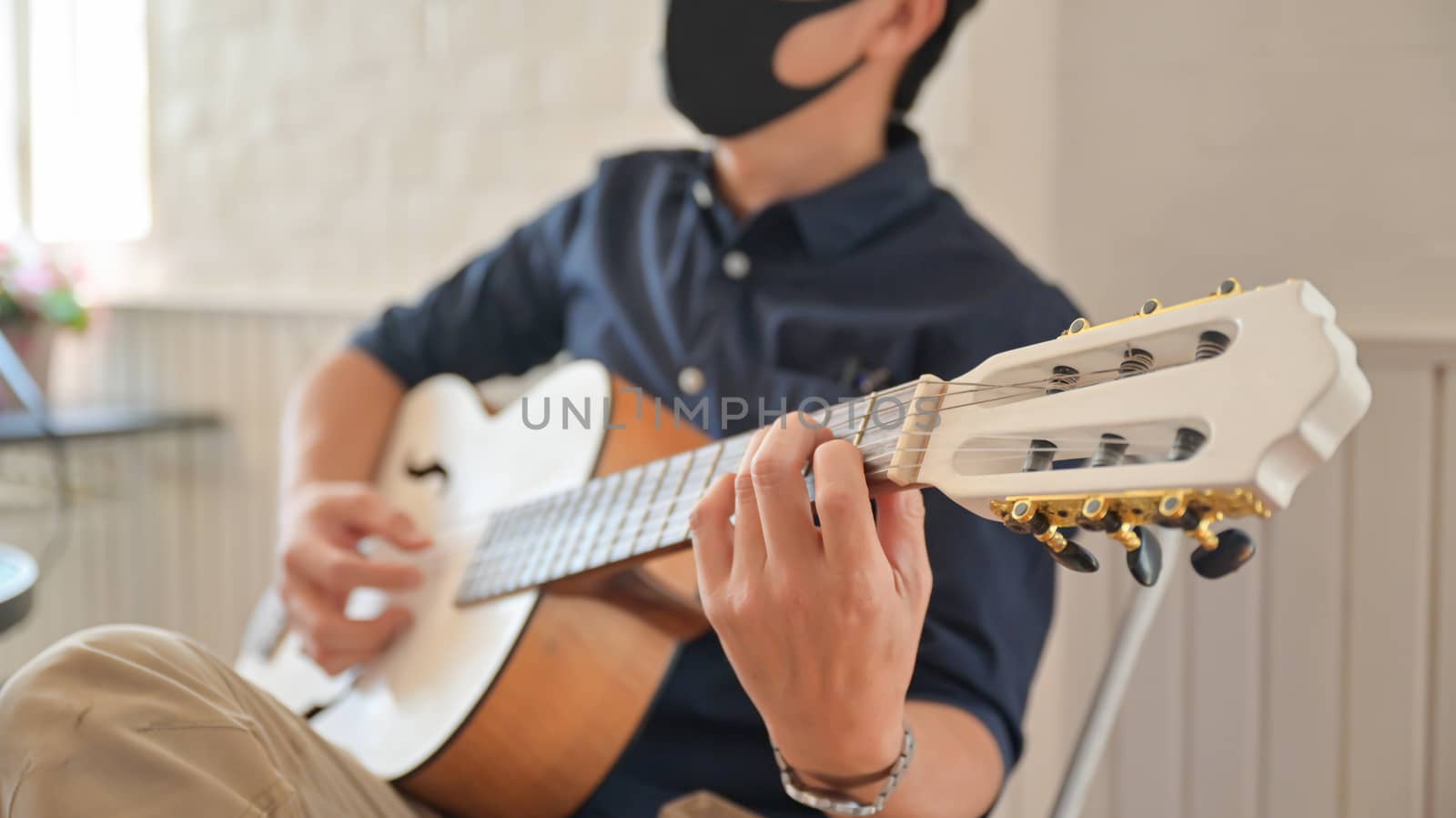 A young man wearing a mask playing guitar at home,Stay at home,W by poungsaed