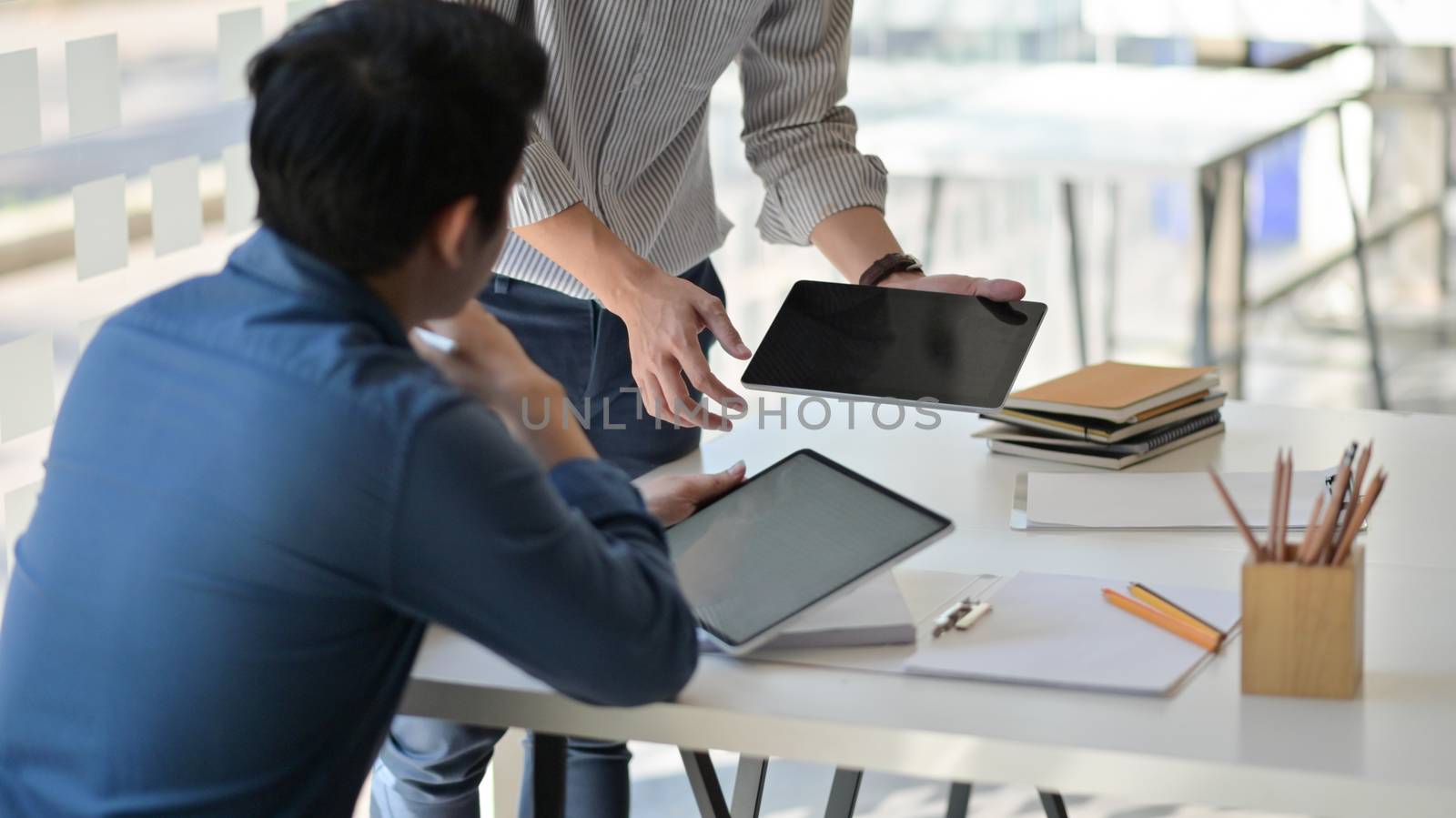 Cropped shot of Two asian men using a tablet. They consulted the job to present clients in a contemporary office.