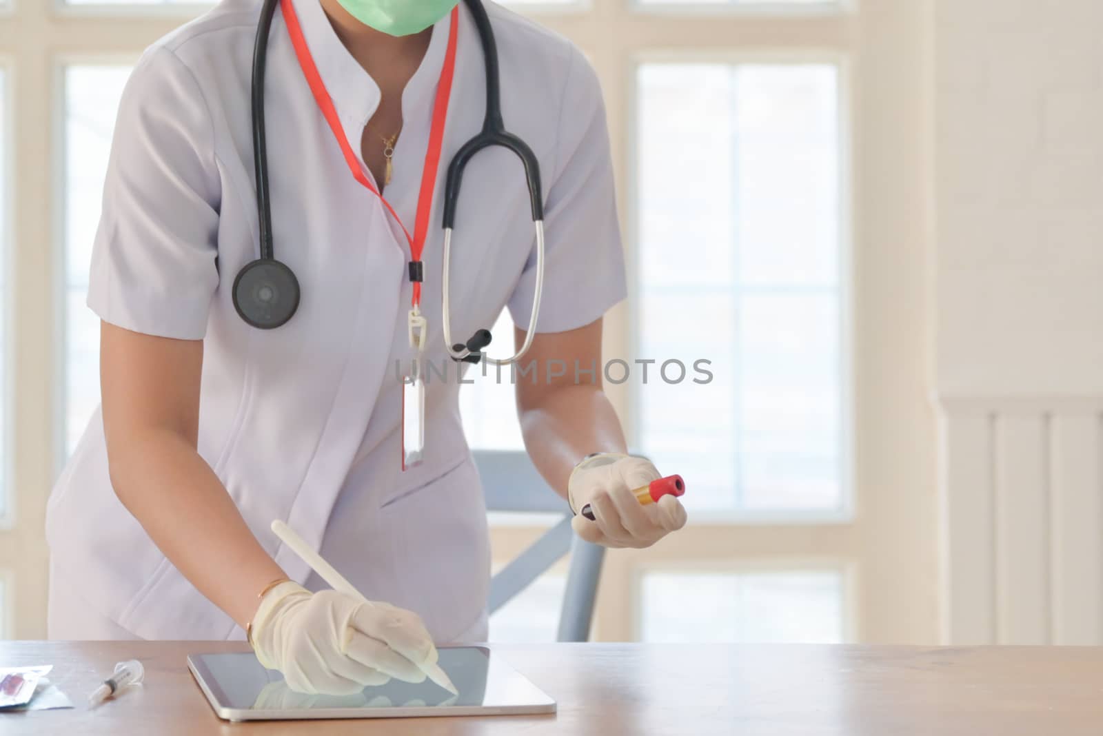 Cropped shot of nurse wearing medical gloves writing on tablet screen and grasping the blood tubes to save data.