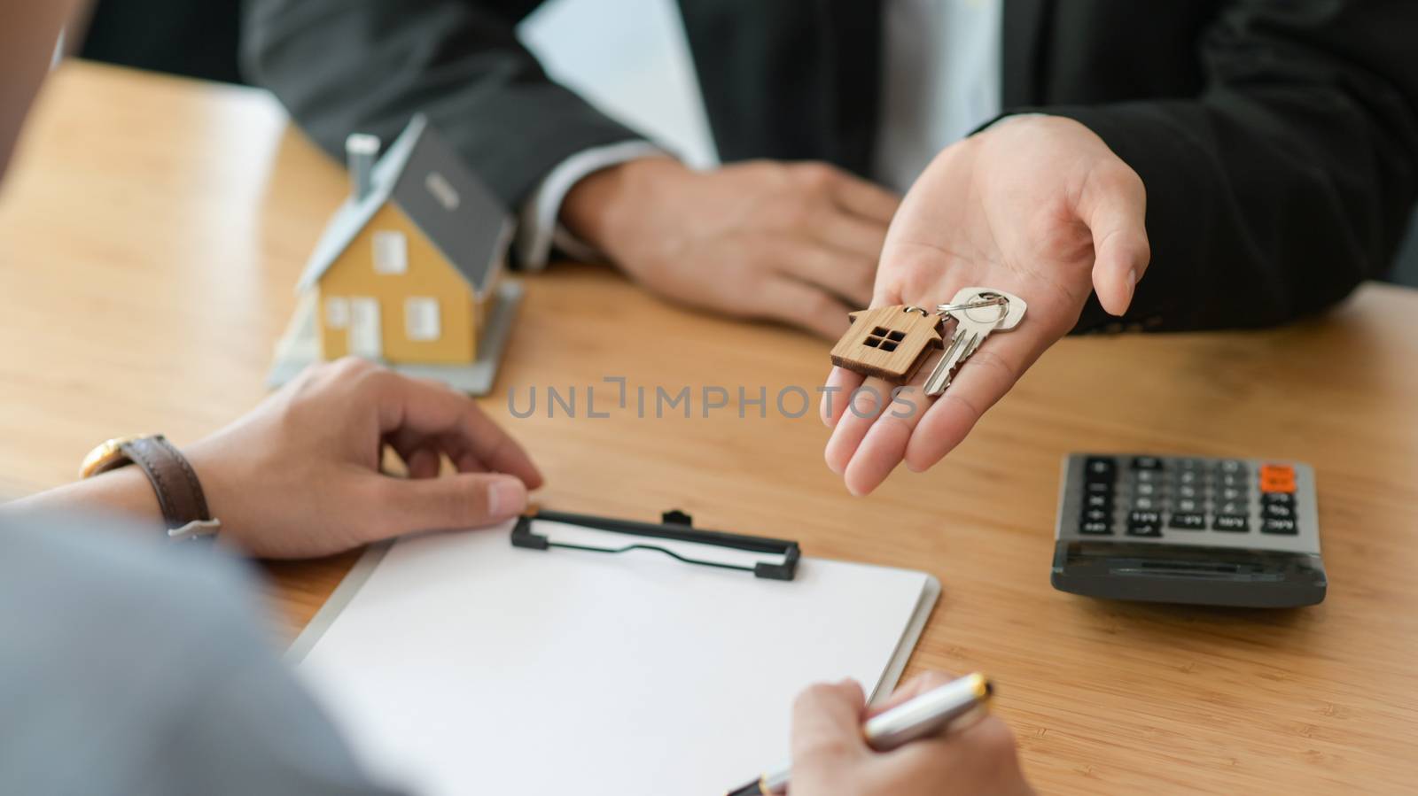 Cropped shot of signing a home purchase contract while the broker holds the house key.