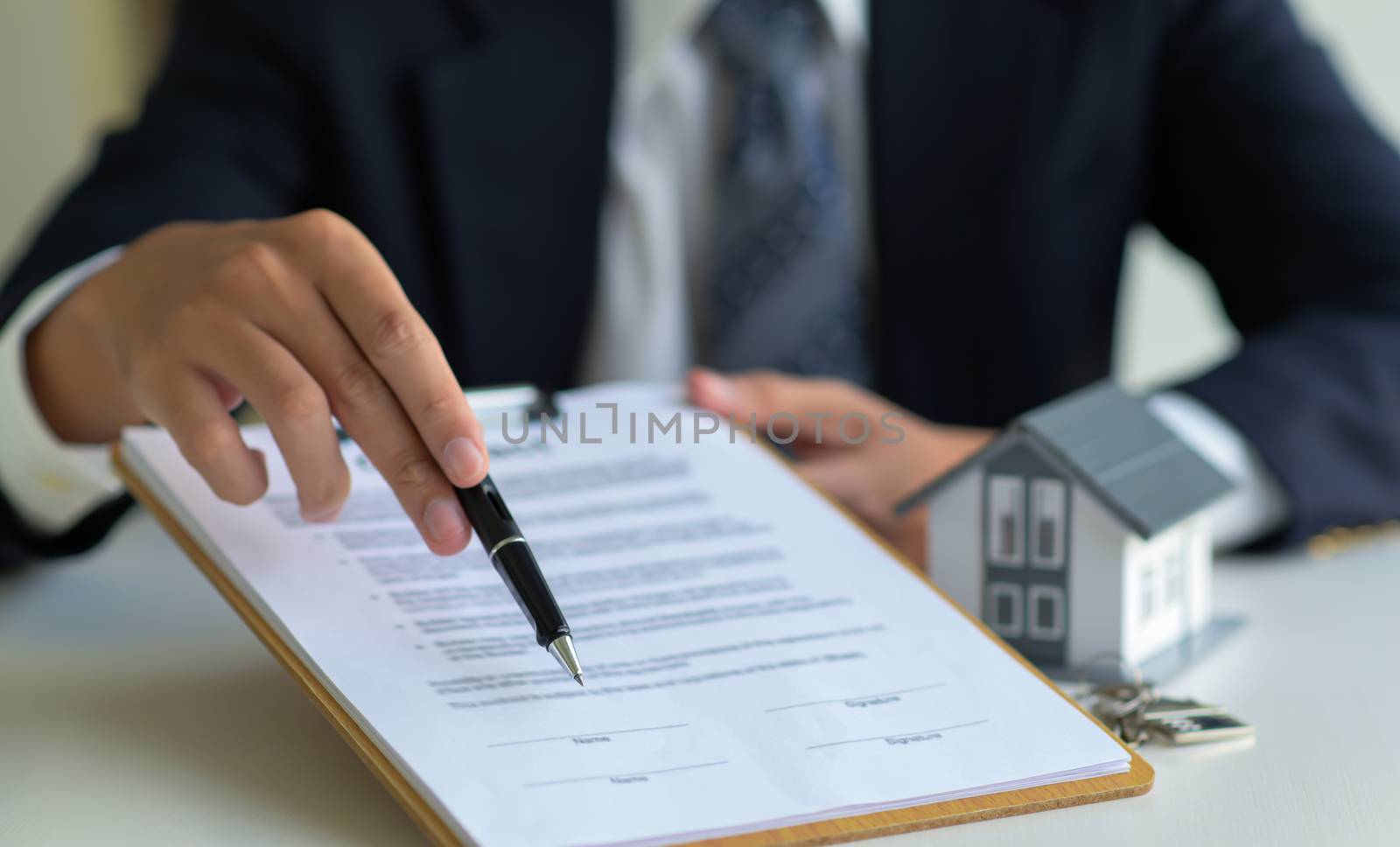 close-up shot of House broker pointing the pen on document signi by poungsaed