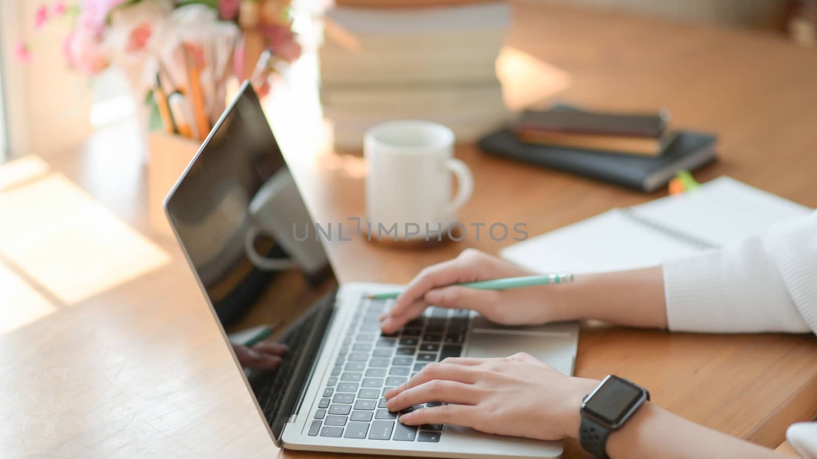 Close up, Young girl's hand is using a laptop on a wooden desk i by poungsaed