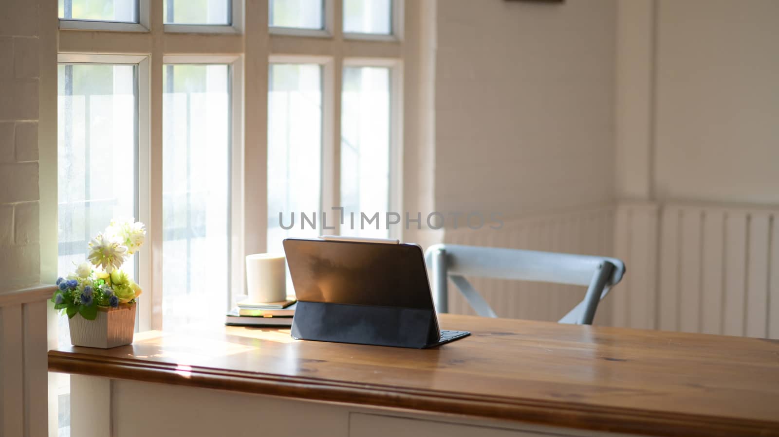 Laptop with a notebook and coffee on a wooden table in the office with beautiful lighting.