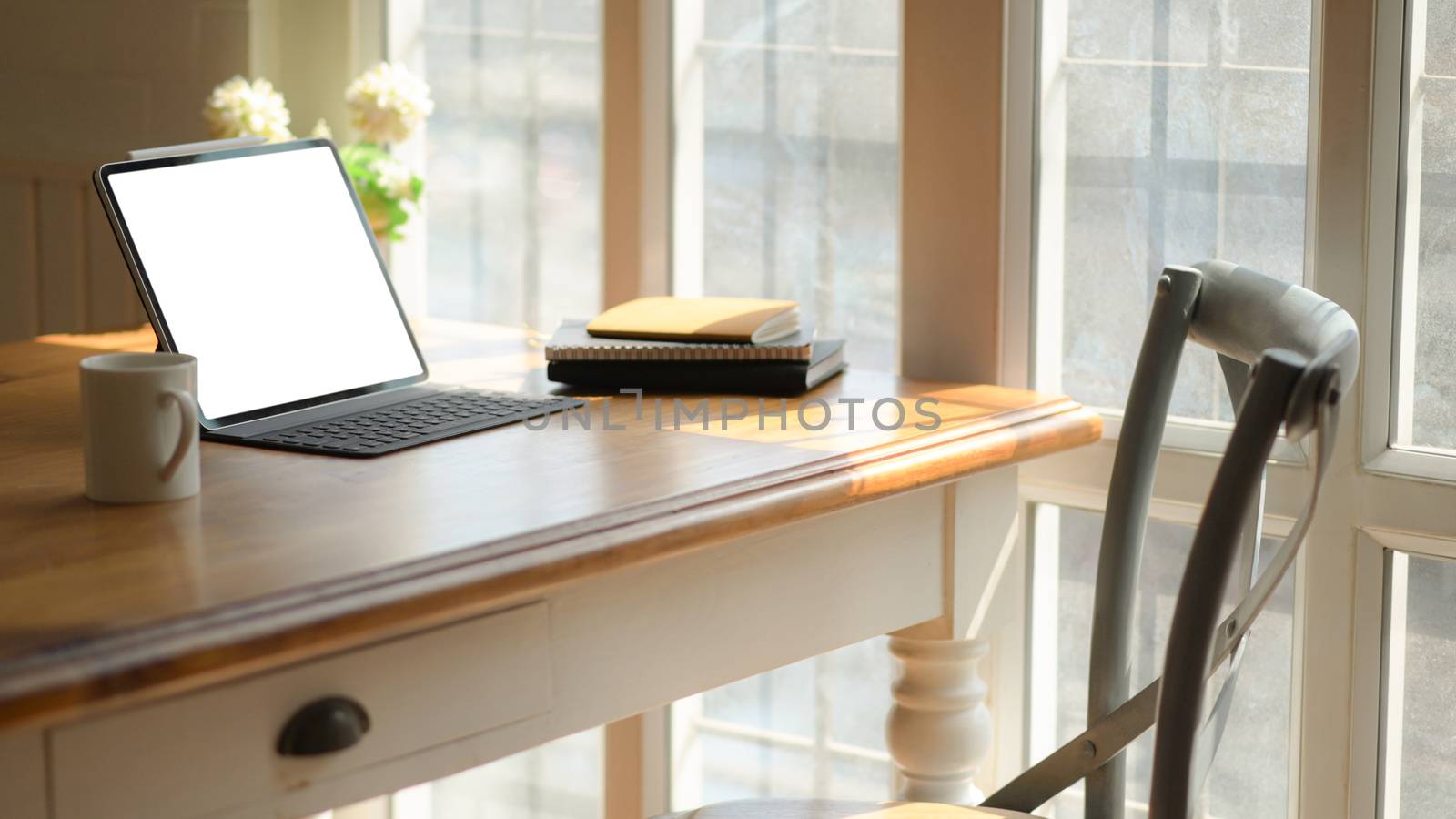 Cropped shot of classic workplace with a laptop, coffee cup and stationary on a wooden table near the window.