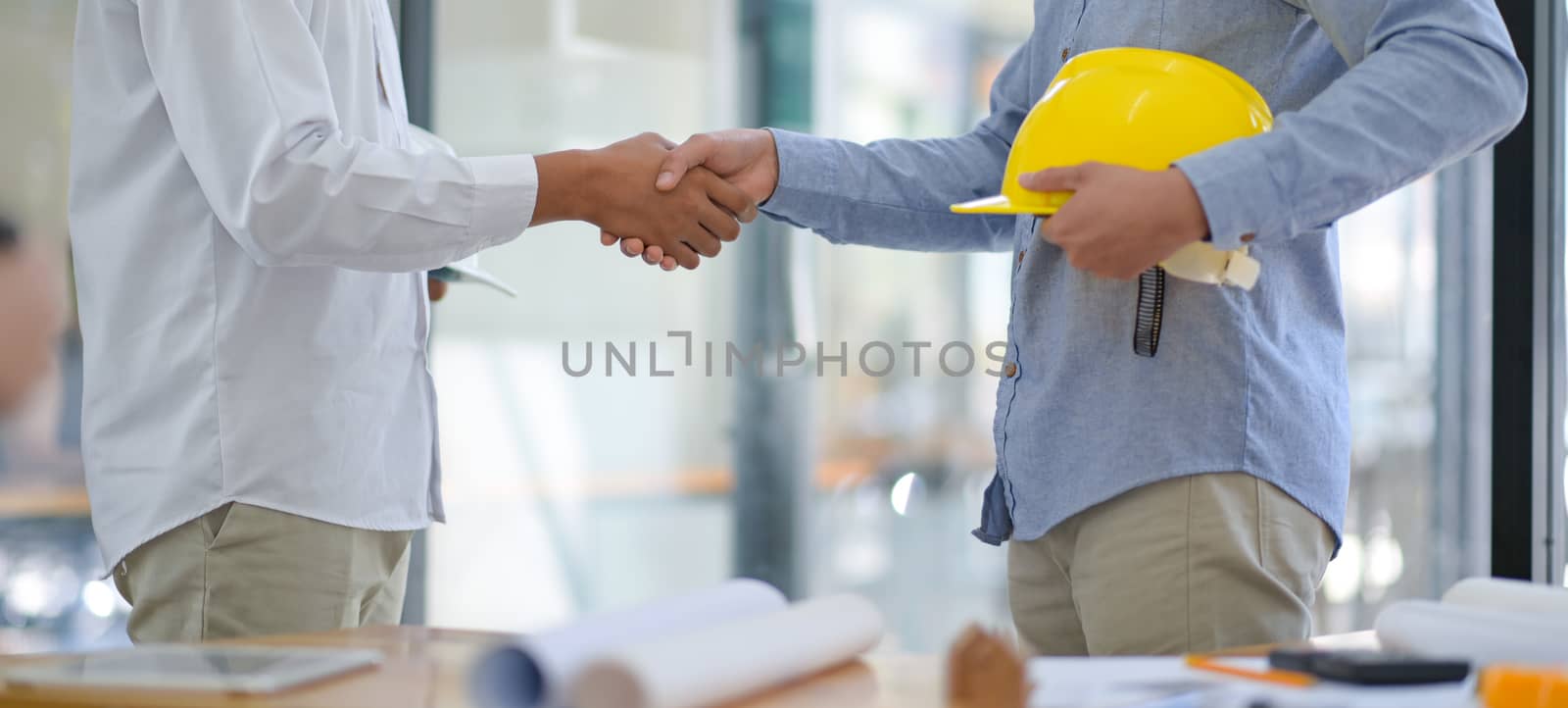 Architects and contractors shake hands to work. by poungsaed